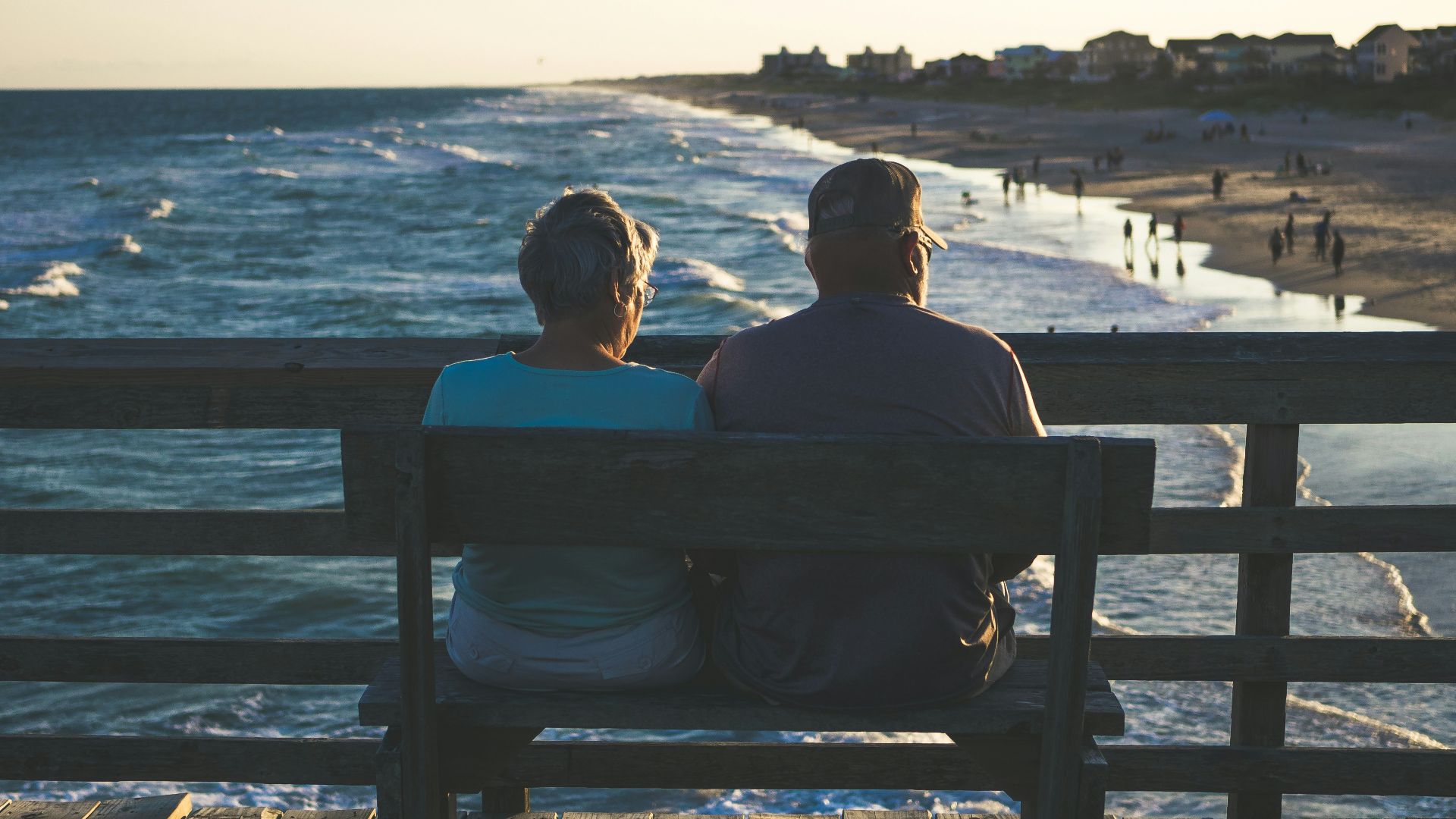 man and woman sitting on bench in front of beach