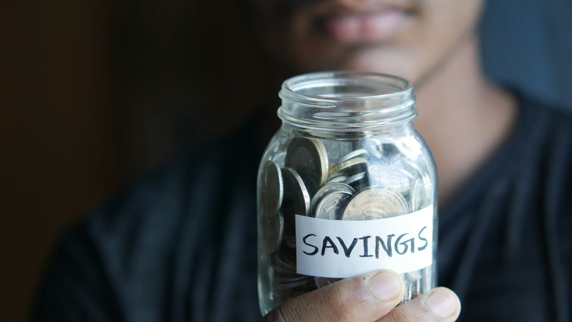 a man holding a jar with a savings label on it