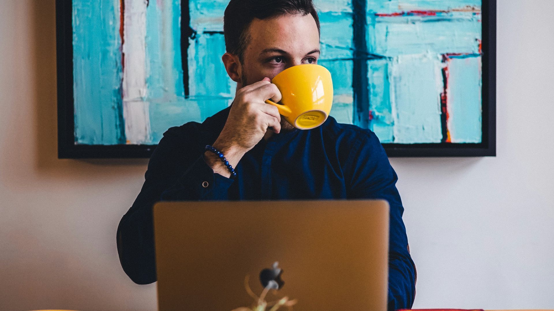 man drinking coffee in front of the laptop computer