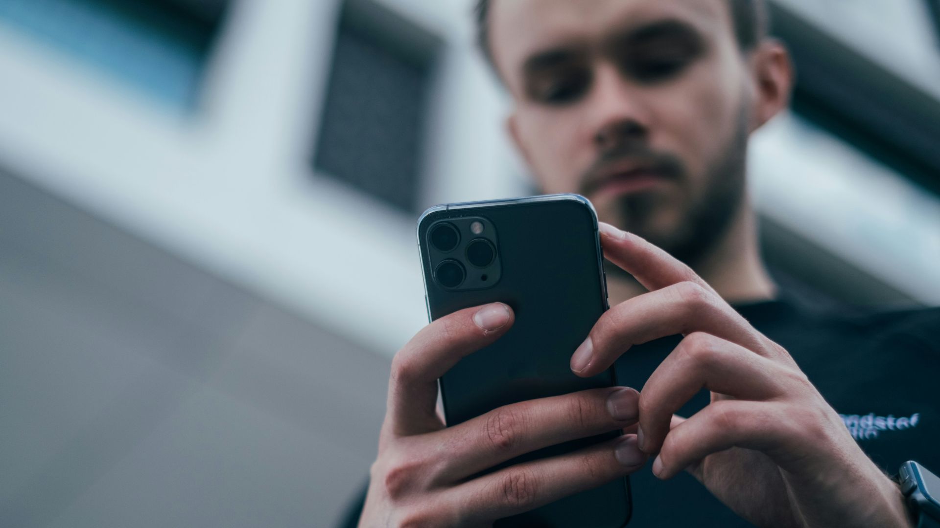 man wearing black sweater using smartphone