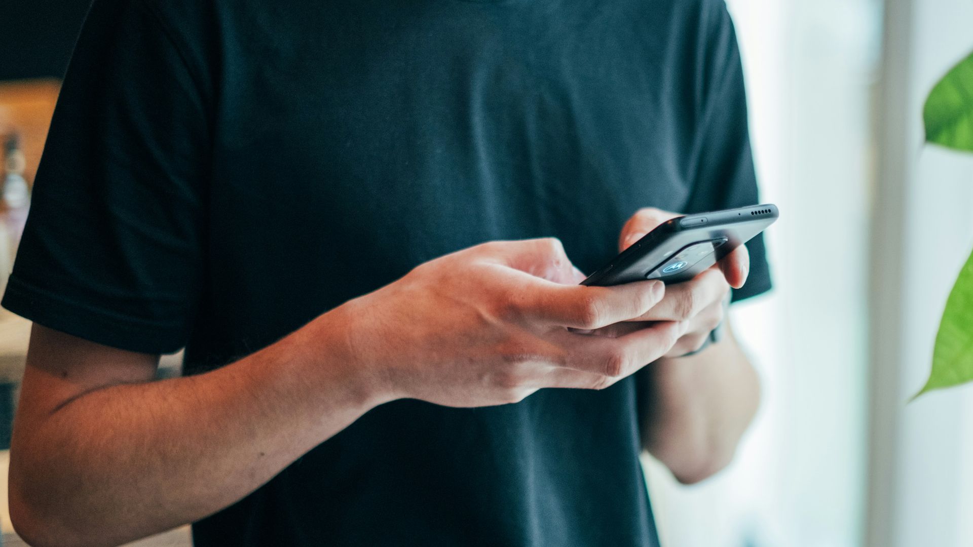 man in black crew-neck top using smartphone
