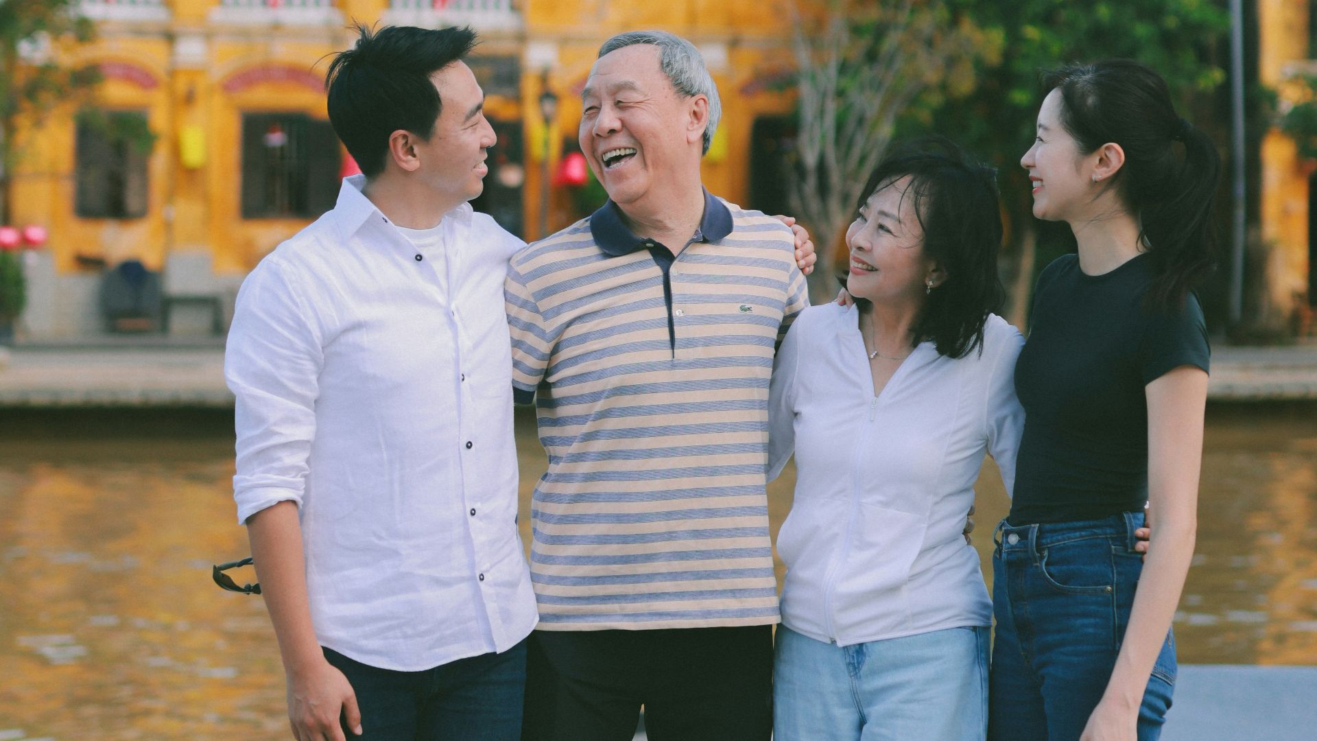 A family poses together in front of colorful buildings.