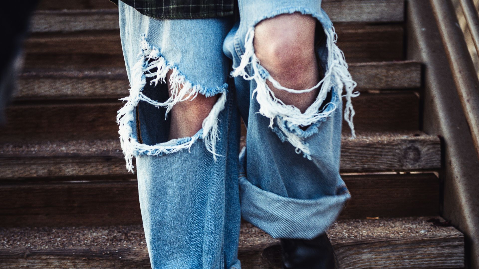 a person's legs in jeans and a blue shirt on a wooden staircase