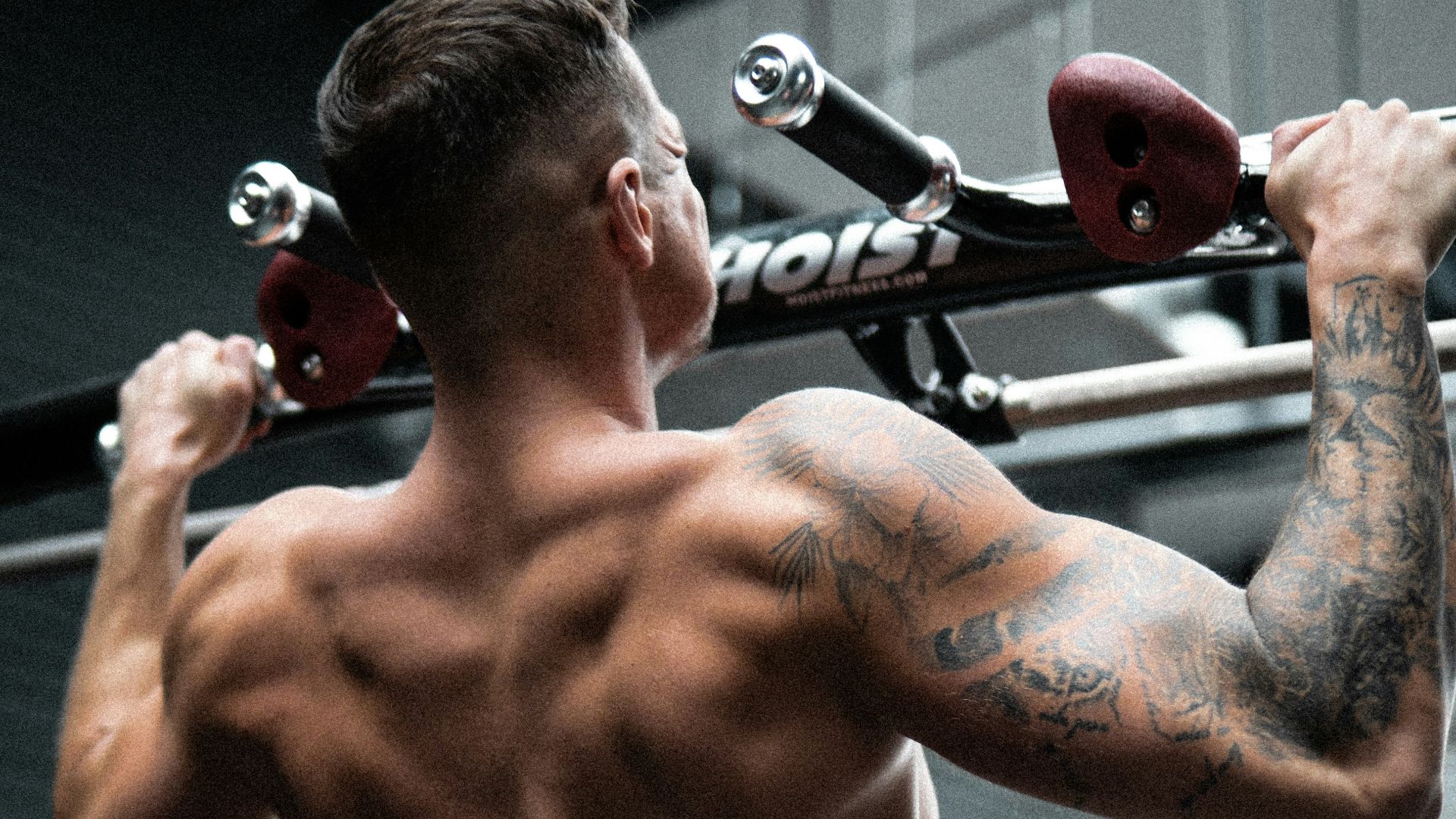 topless man in black shorts holding red and black kettle bell