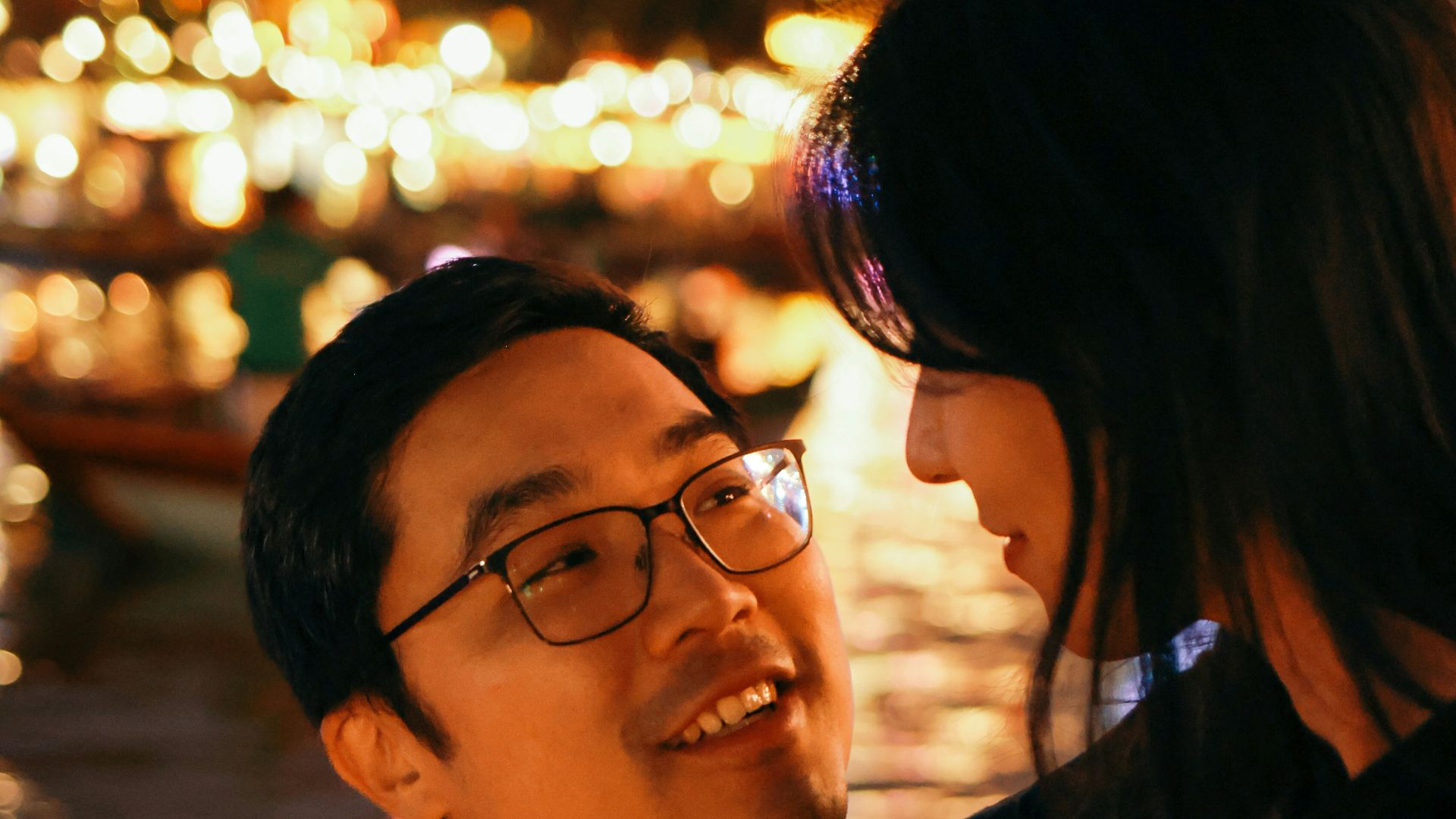 Couple looking at each other with city lights behind