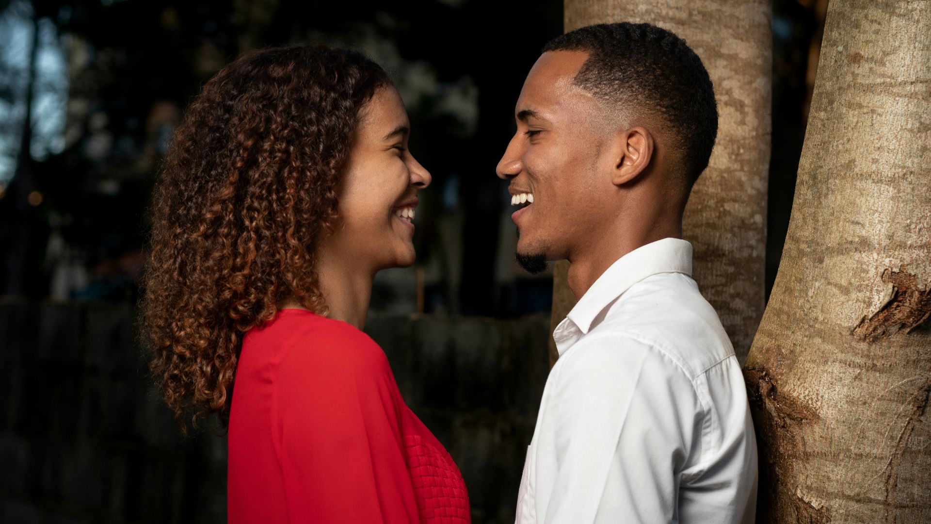 man in white dress shirt kissing woman in red dress