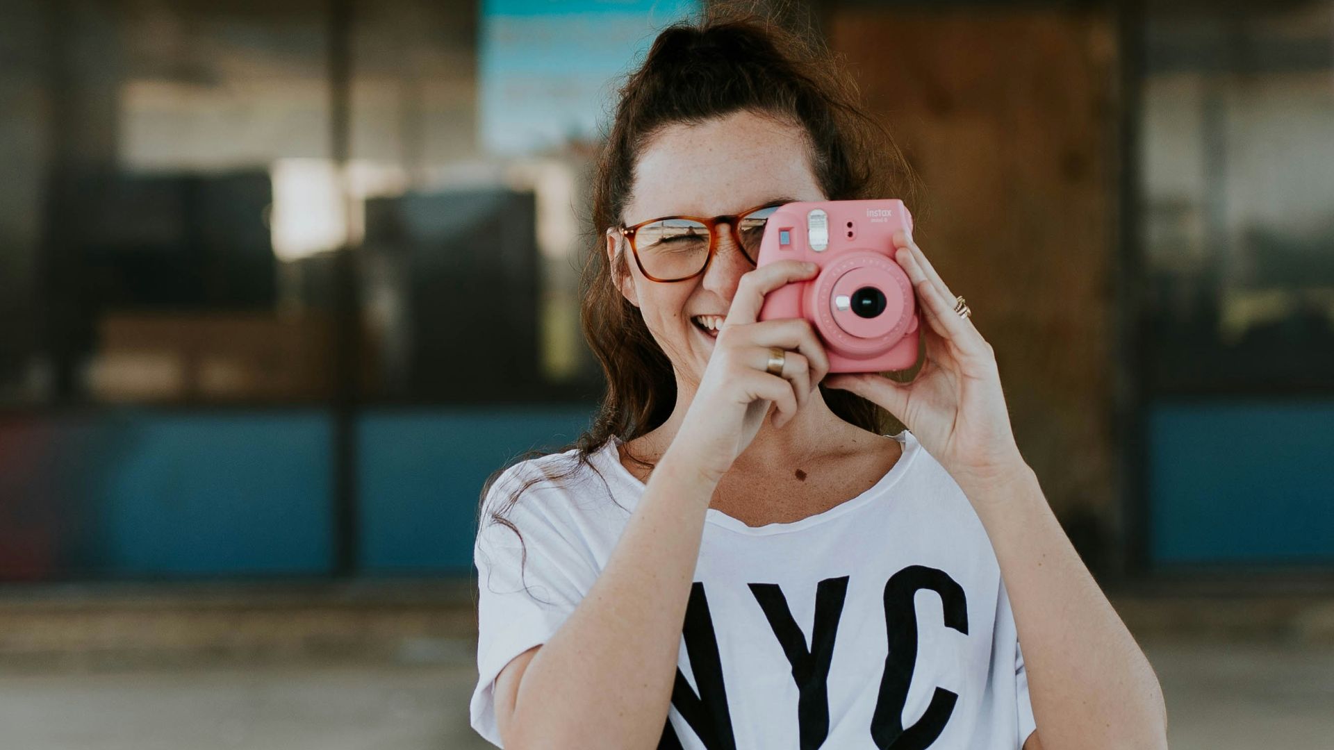 smiling woman holding pink camera