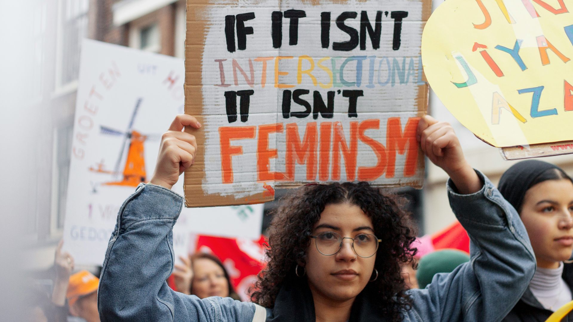woman in blue denim jacket holding white and red signage