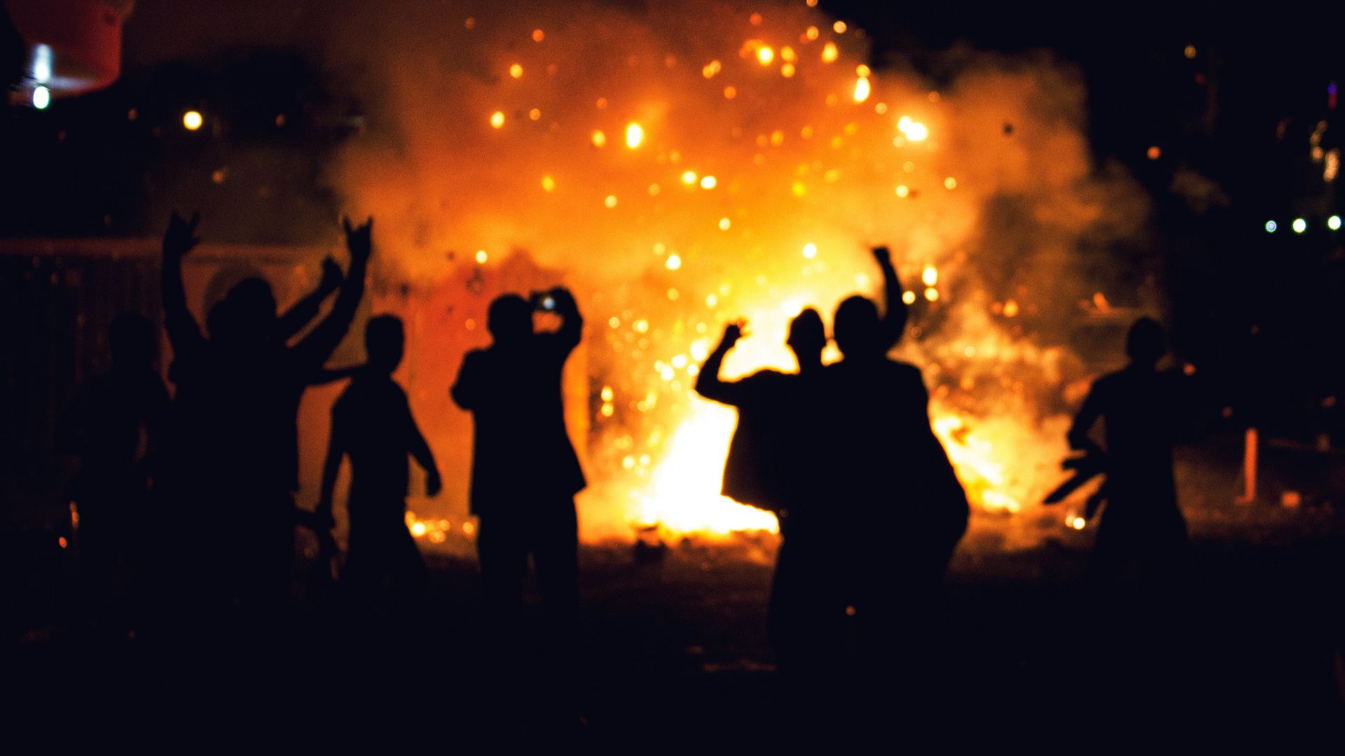 silhouette of people standing on field with fireworks