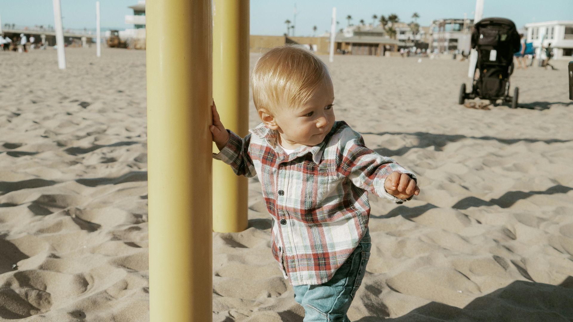 boy in red white and blue plaid button up shirt standing on beach sand during daytime