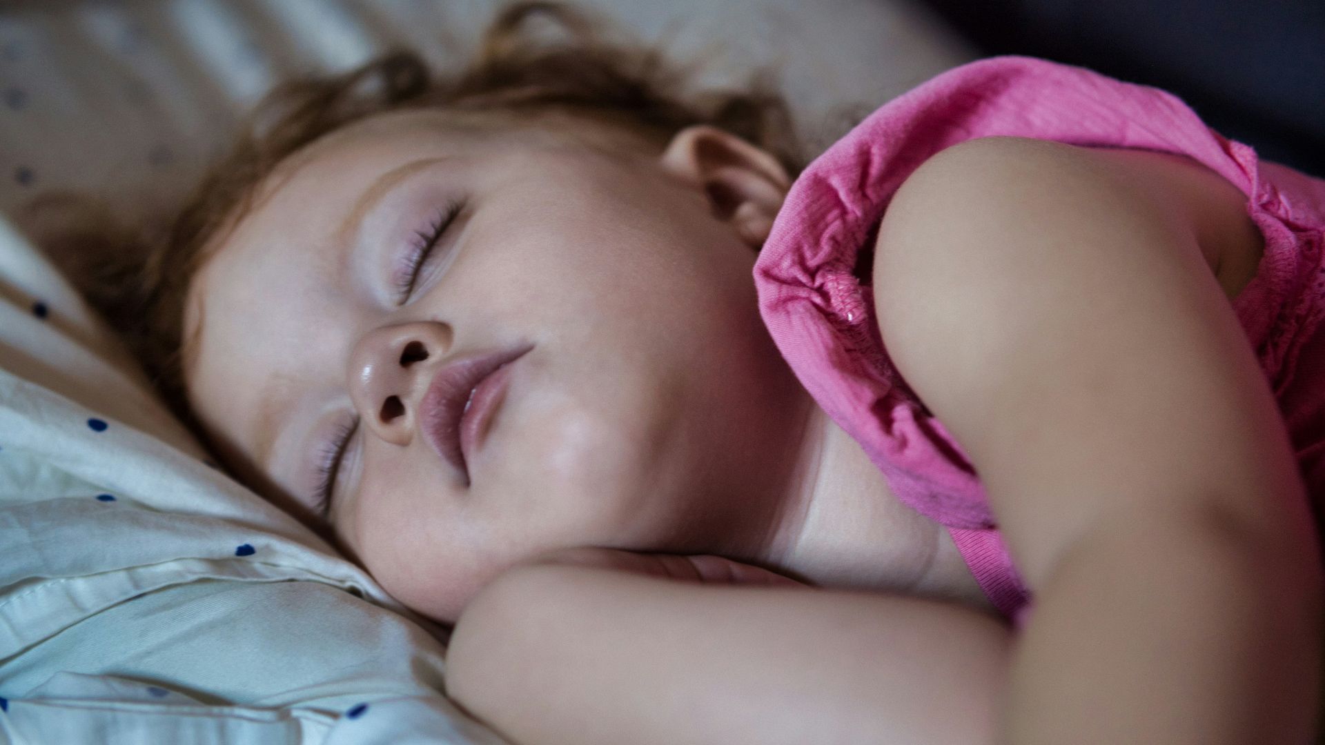 a little girl sleeping on a bed with her eyes closed