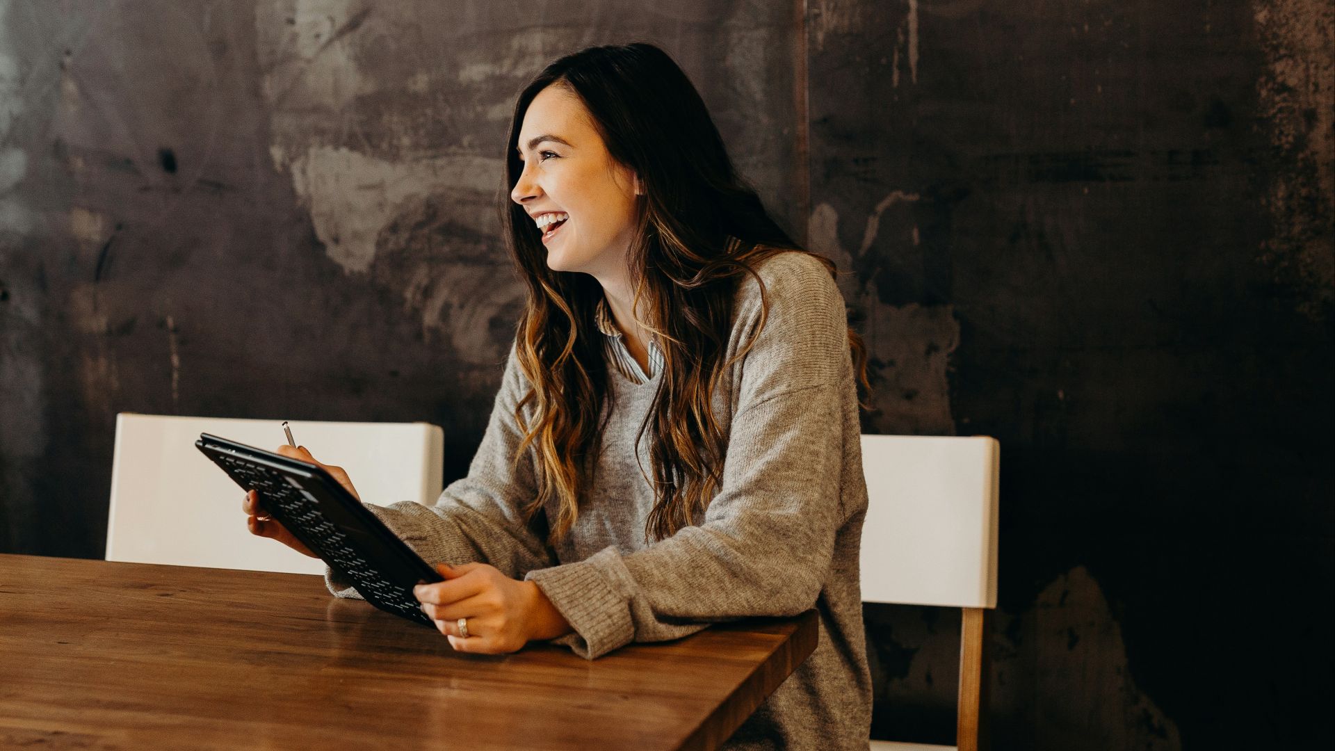 woman sitting around table holding tablet