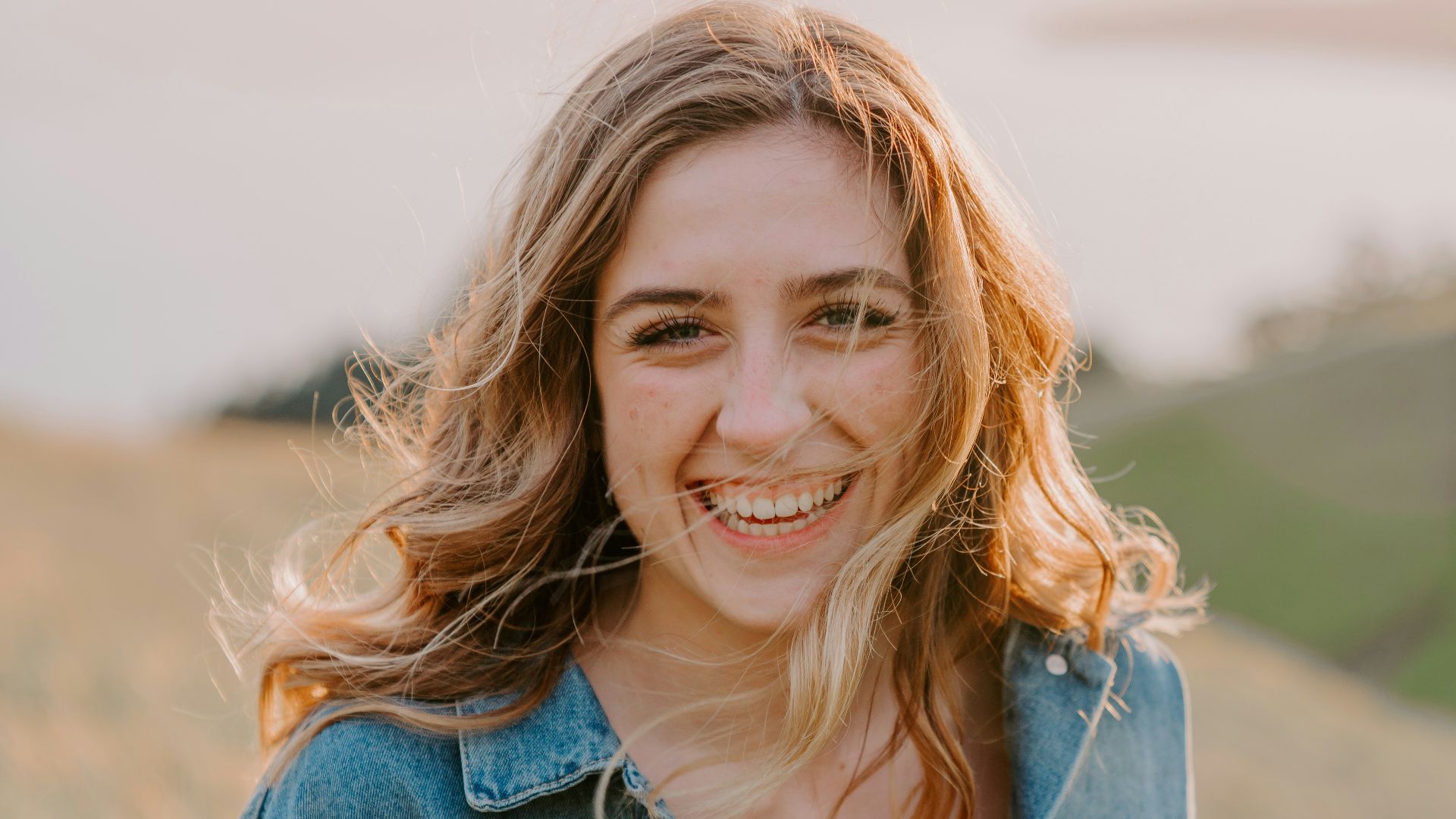 smiling woman sitting on grass during daytime