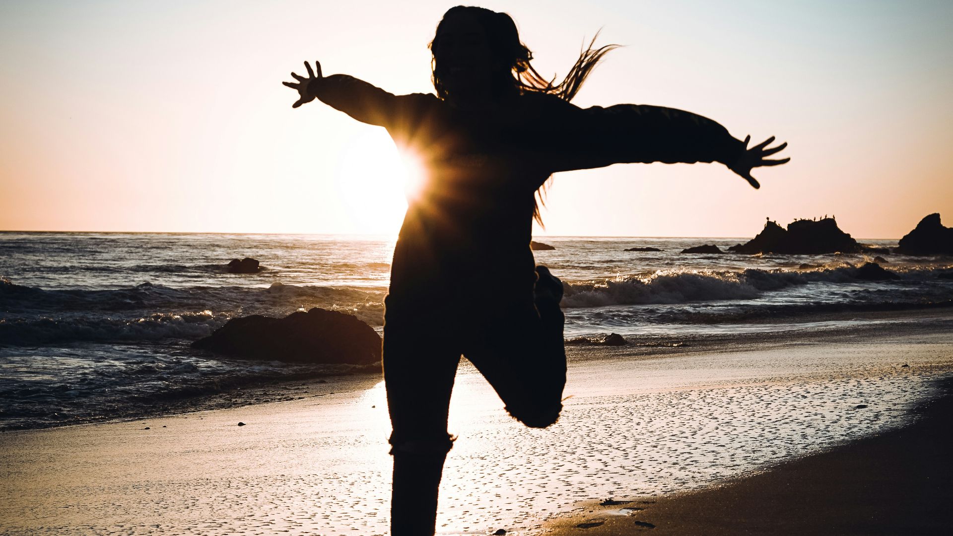 silhouette of woman standing on beach during sunset