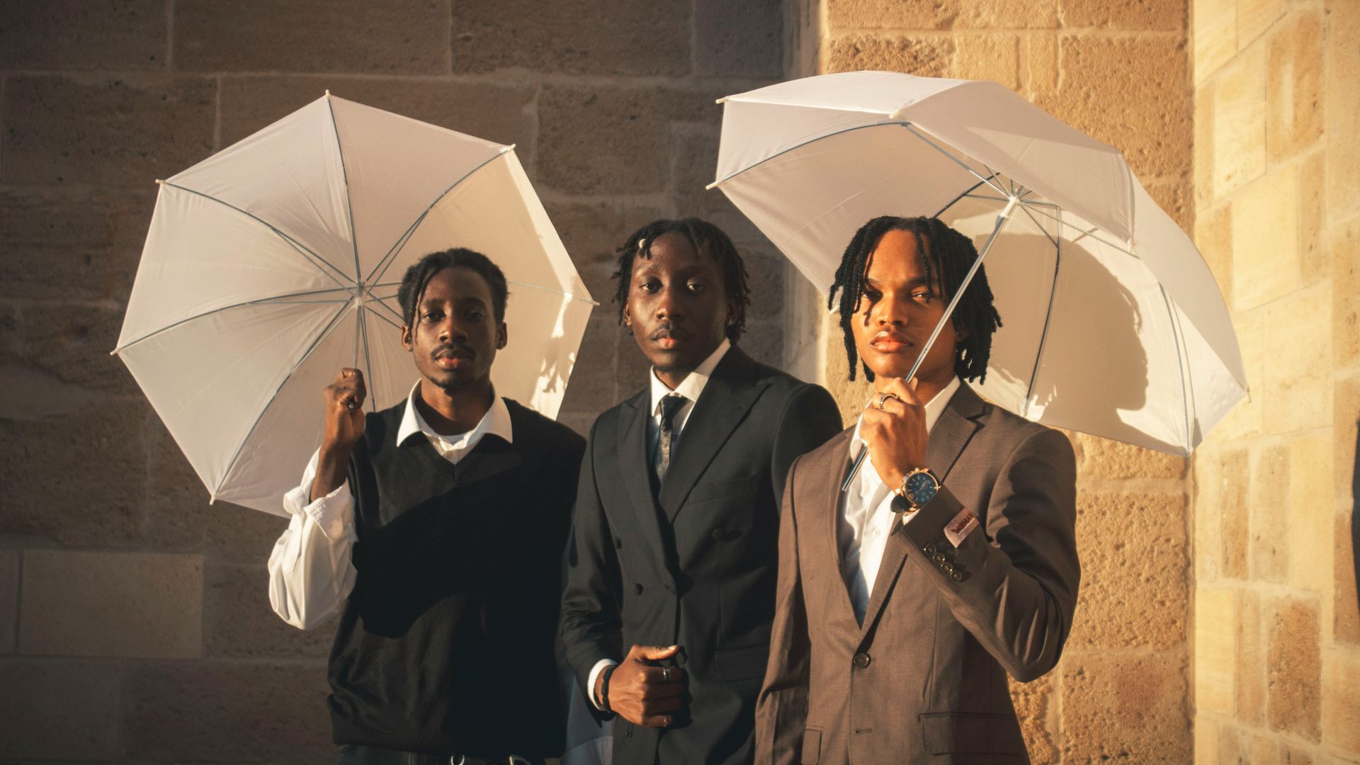 Three young men holding white umbrellas outdoors