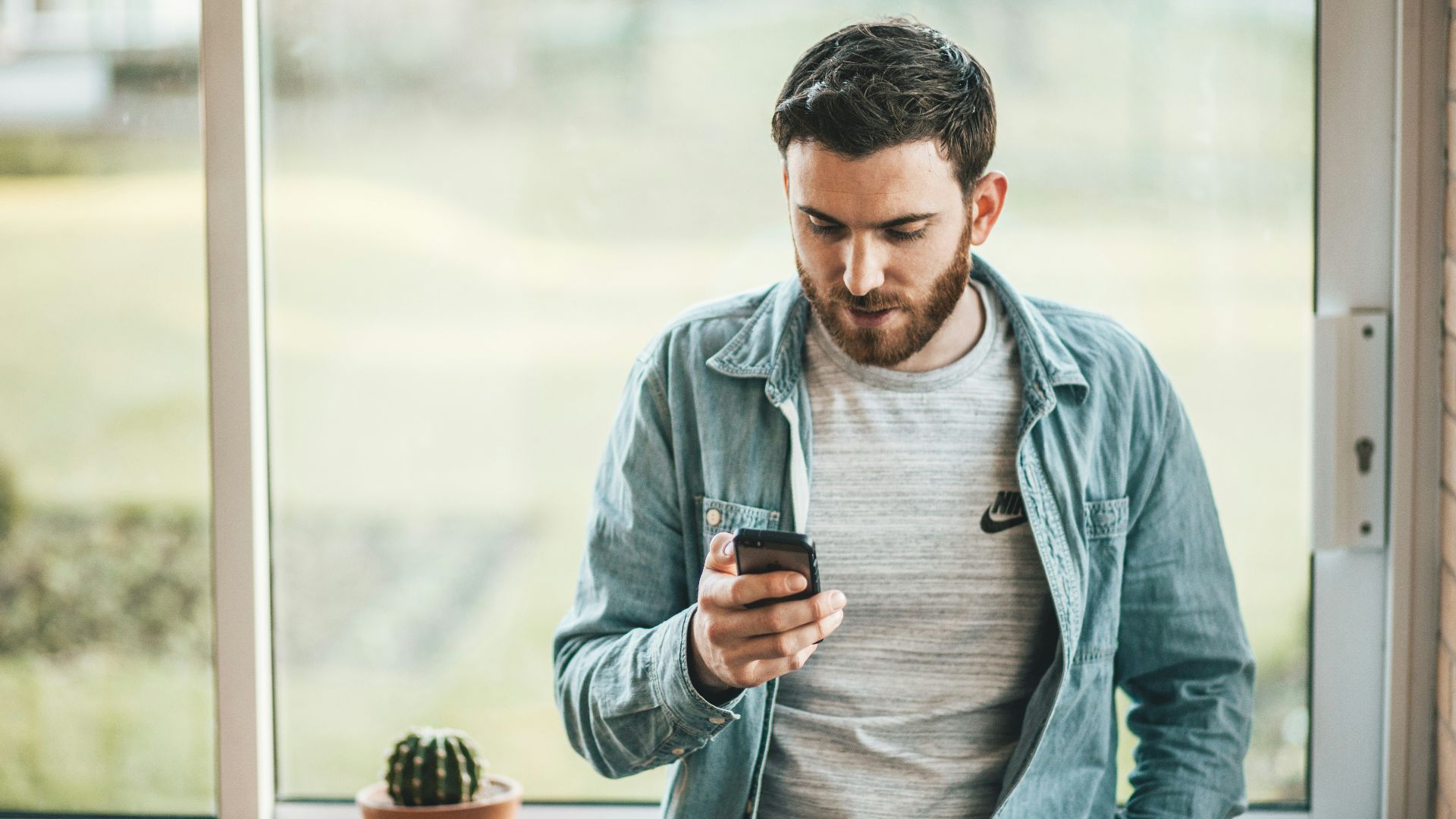 man holding a smartphone near the window
