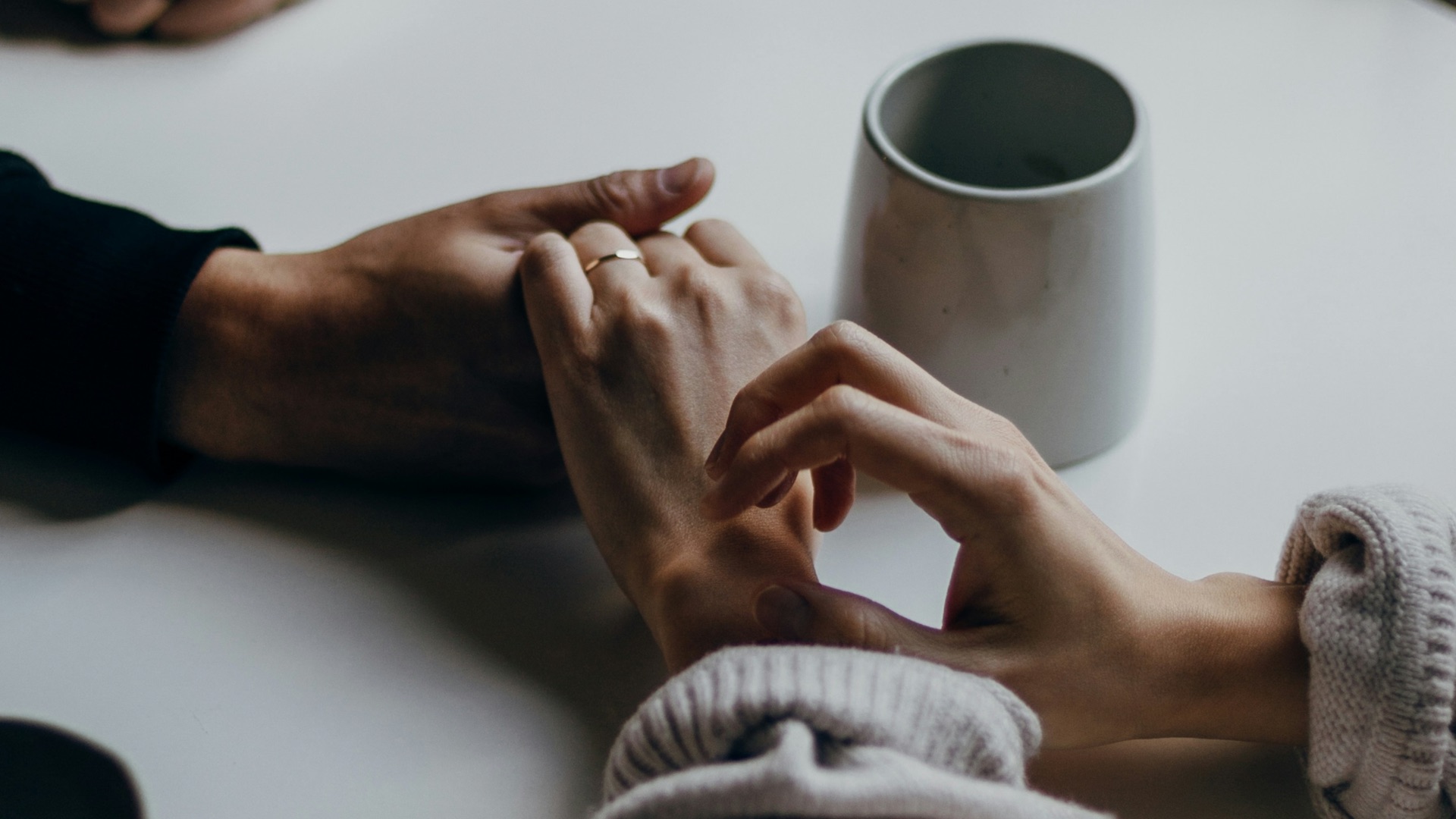 person in black long sleeve shirt holding white ceramic mug