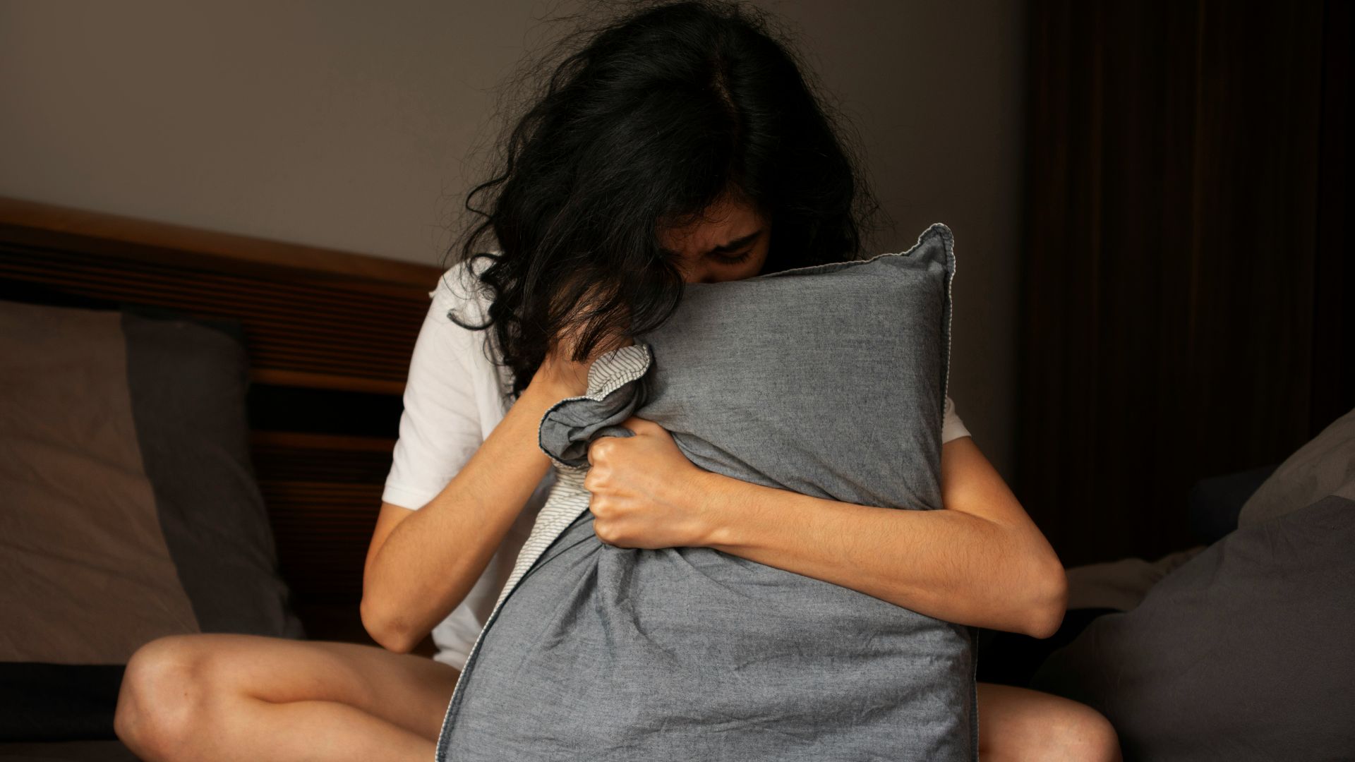 A woman sitting on a bed holding a pillow
