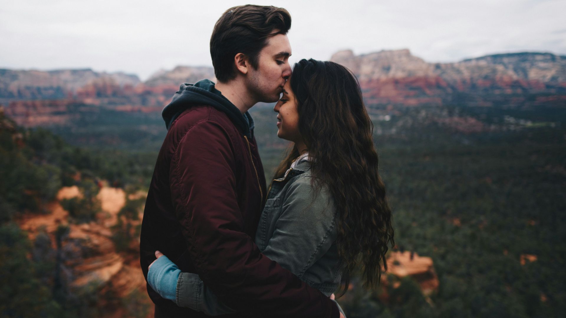 man kissing woman's forehead