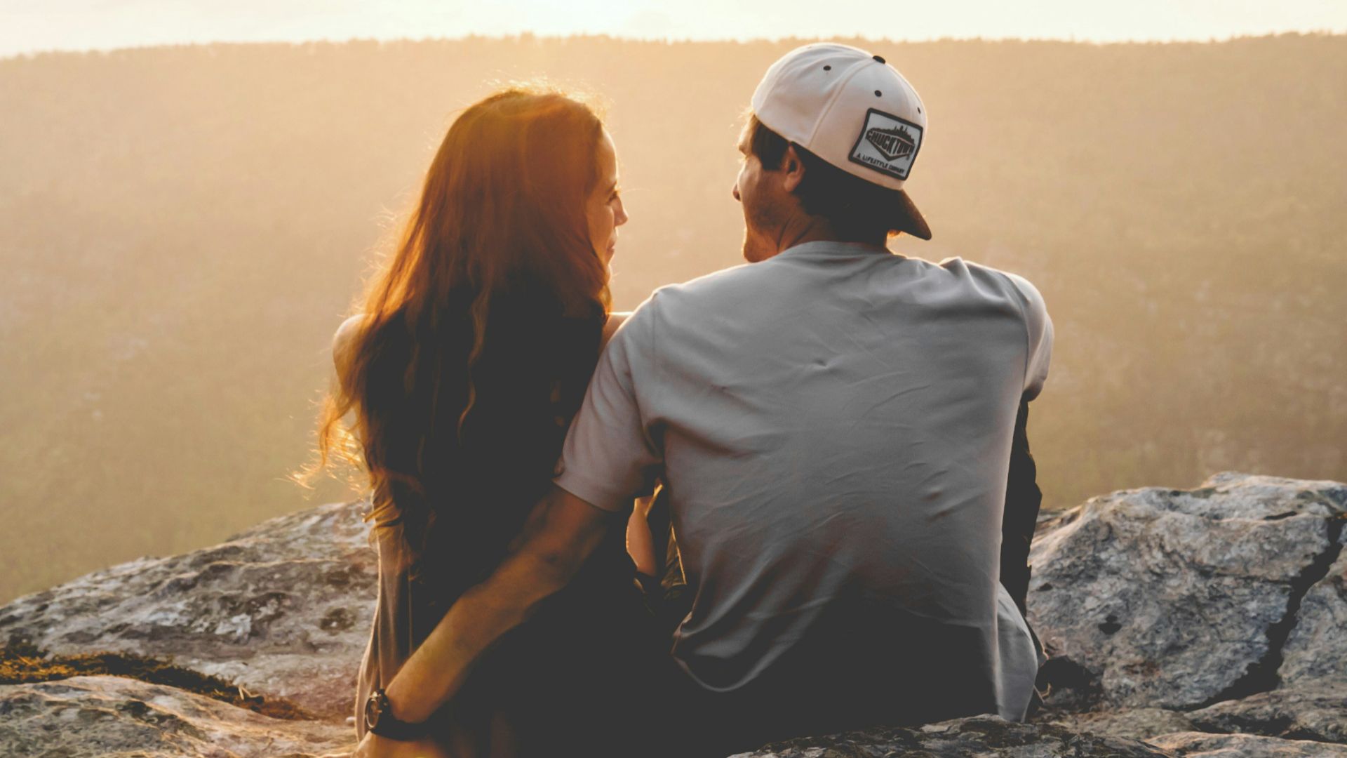 man and woman sitting on rock during daytime