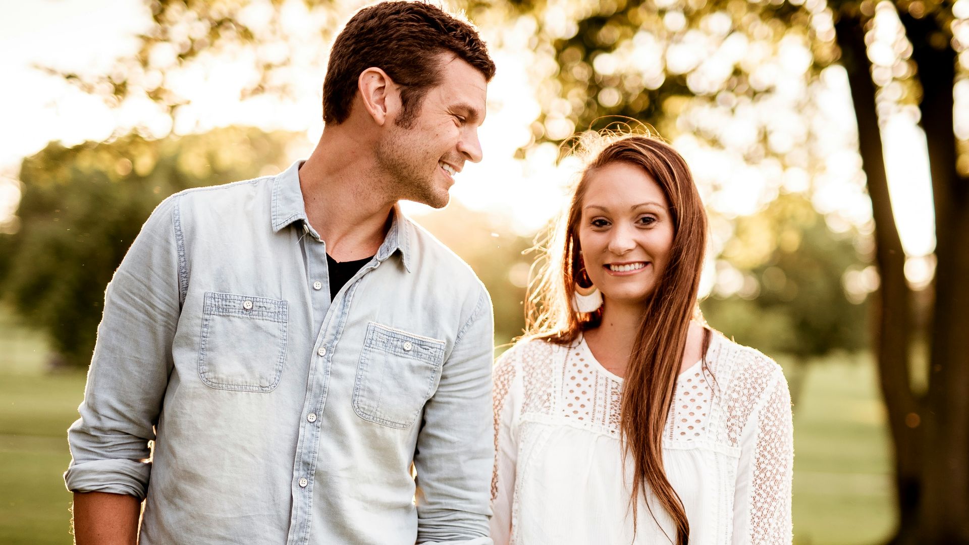 man holding hand of woman standing near tree