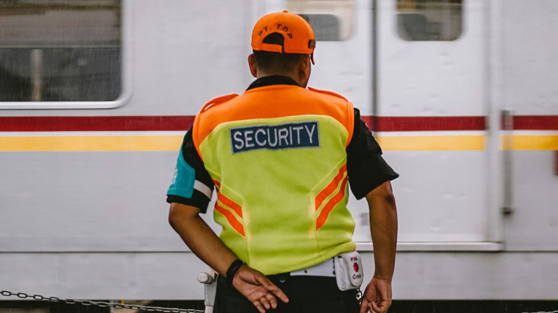 man in orange helmet and green and blue stripe polo shirt standing beside white and red