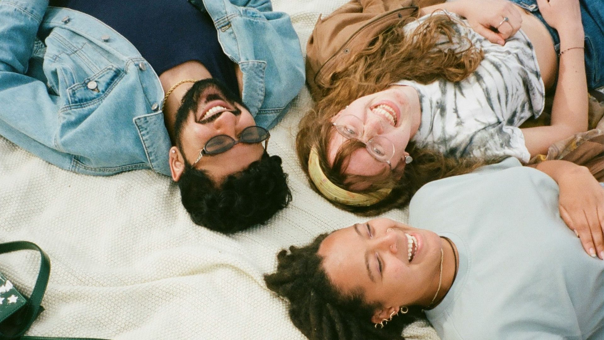man in blue button up shirt lying on white bed