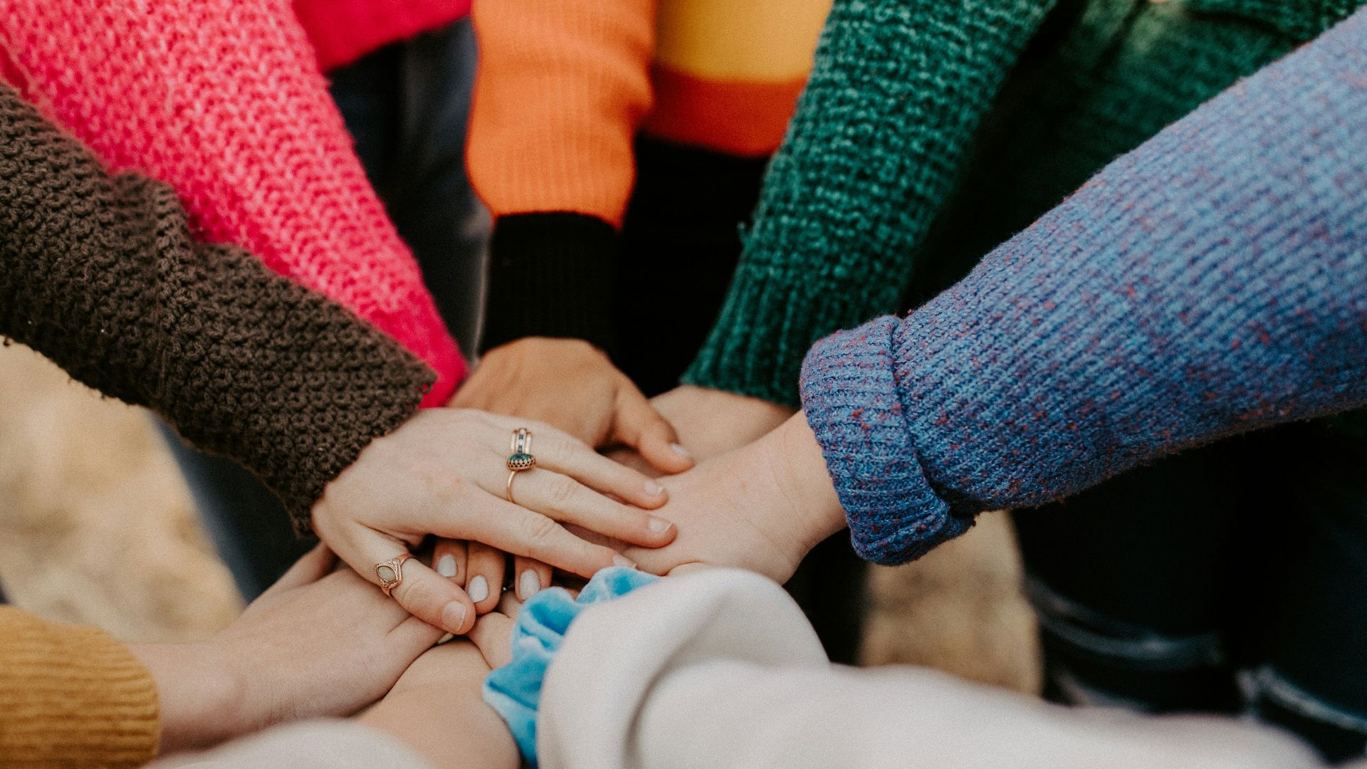 person in red sweater holding babys hand