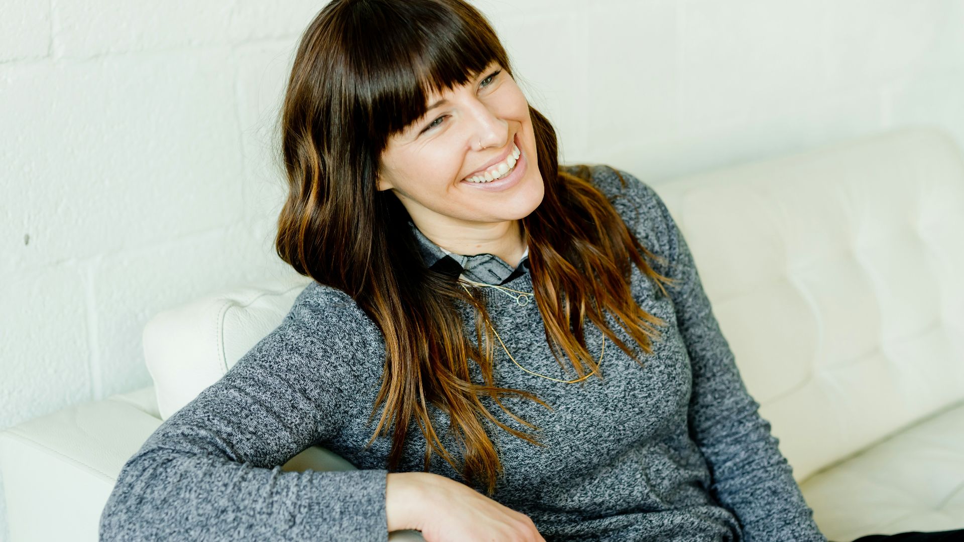woman in gray sweater sitting on white chair
