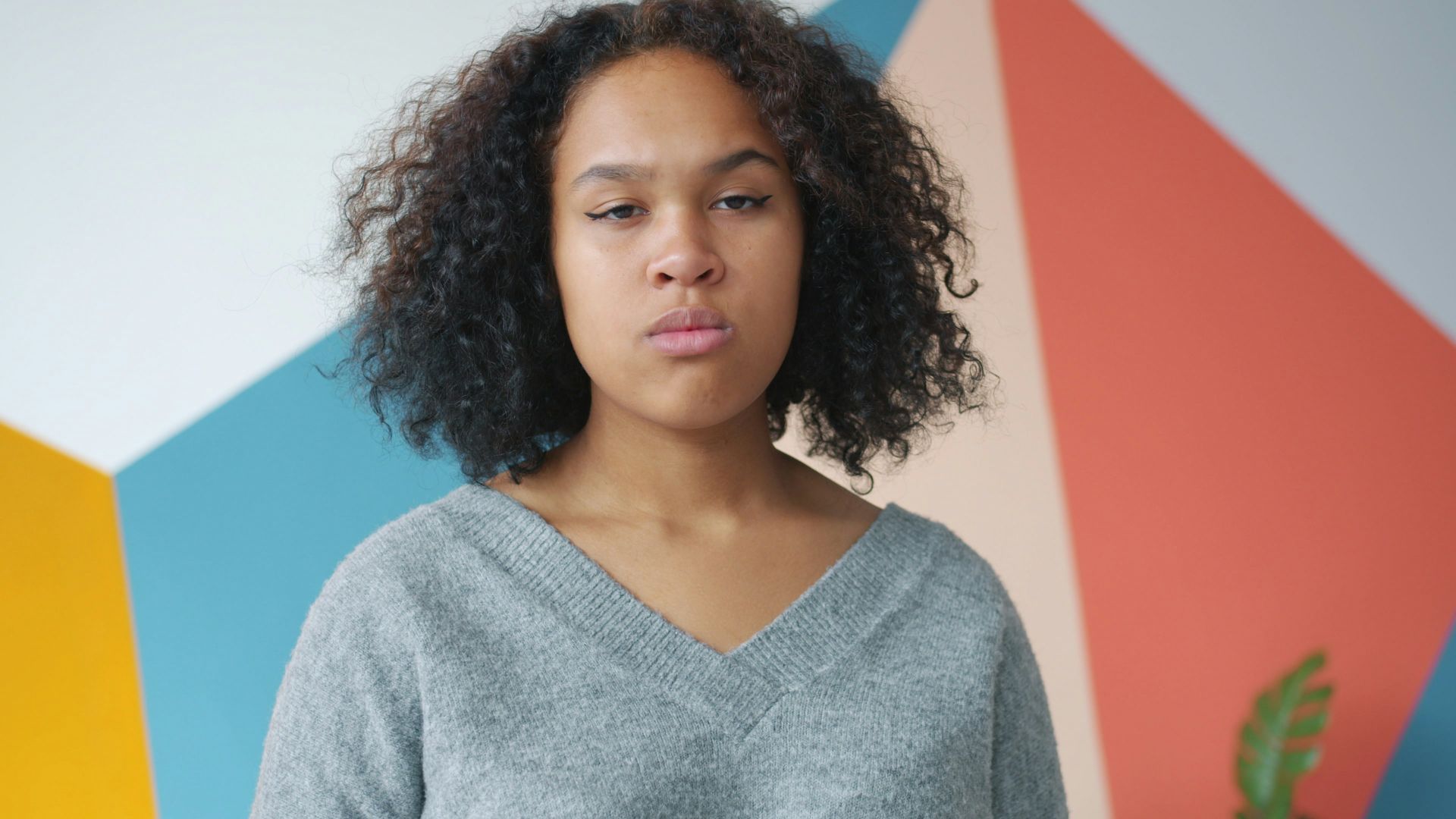 Young woman with curly hair against colorful wall