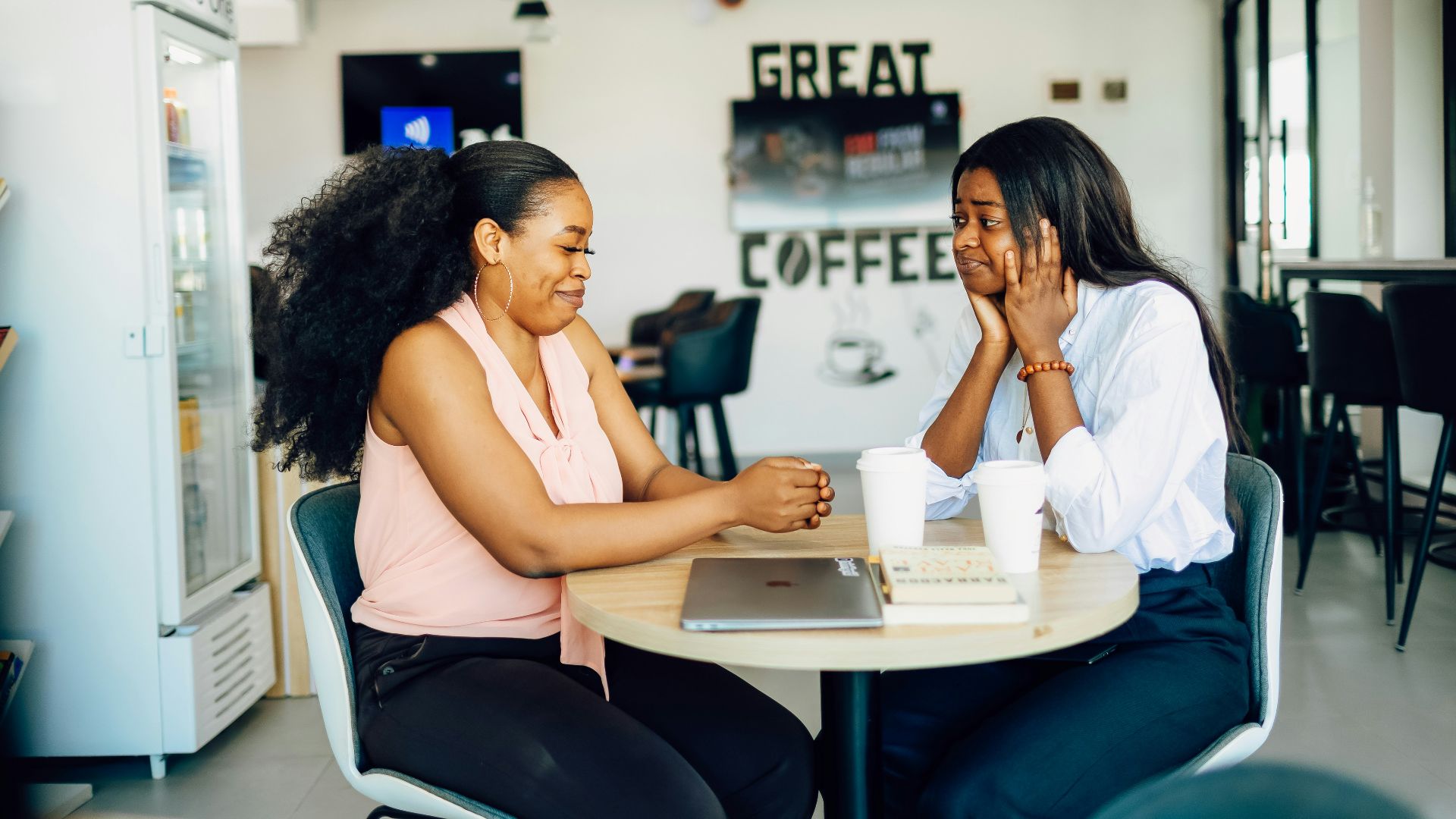 A couple of women sitting at a table with a laptop