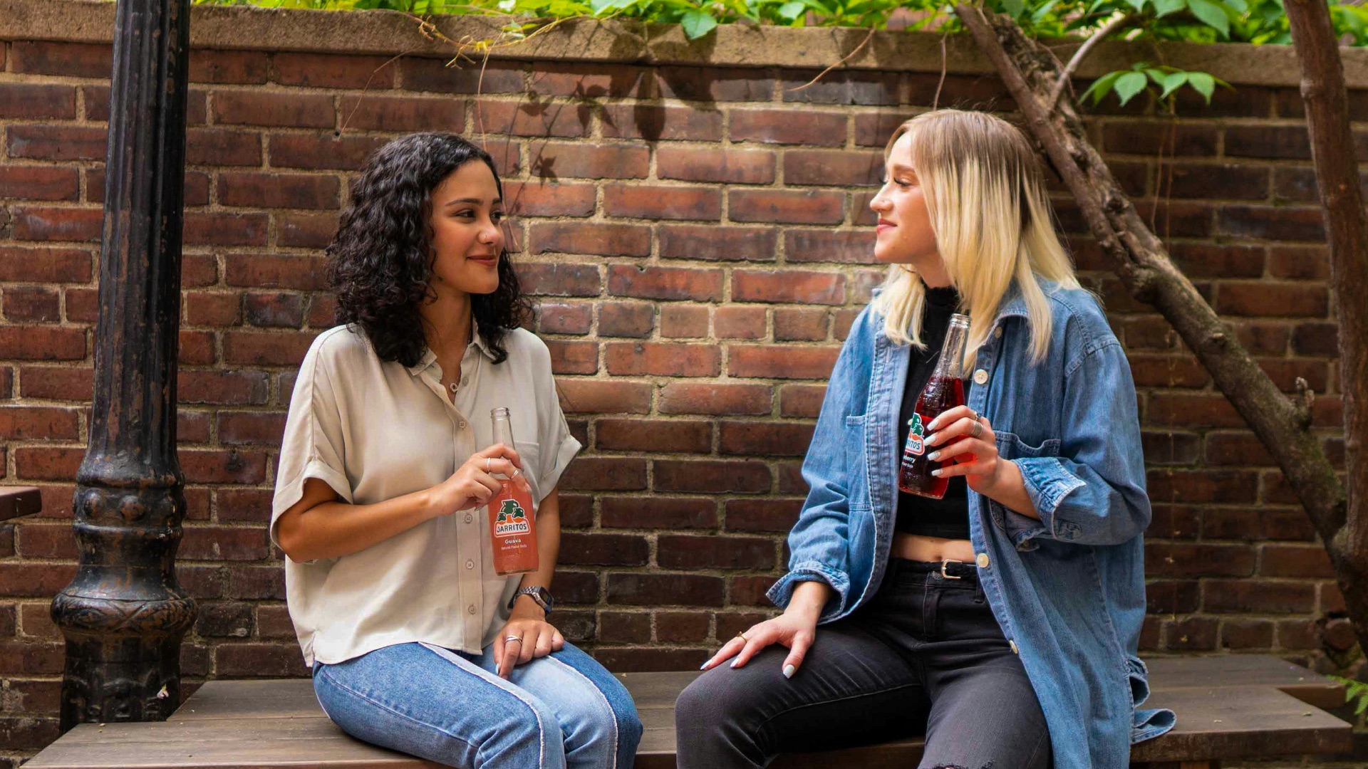 2 women sitting on brown wooden bench