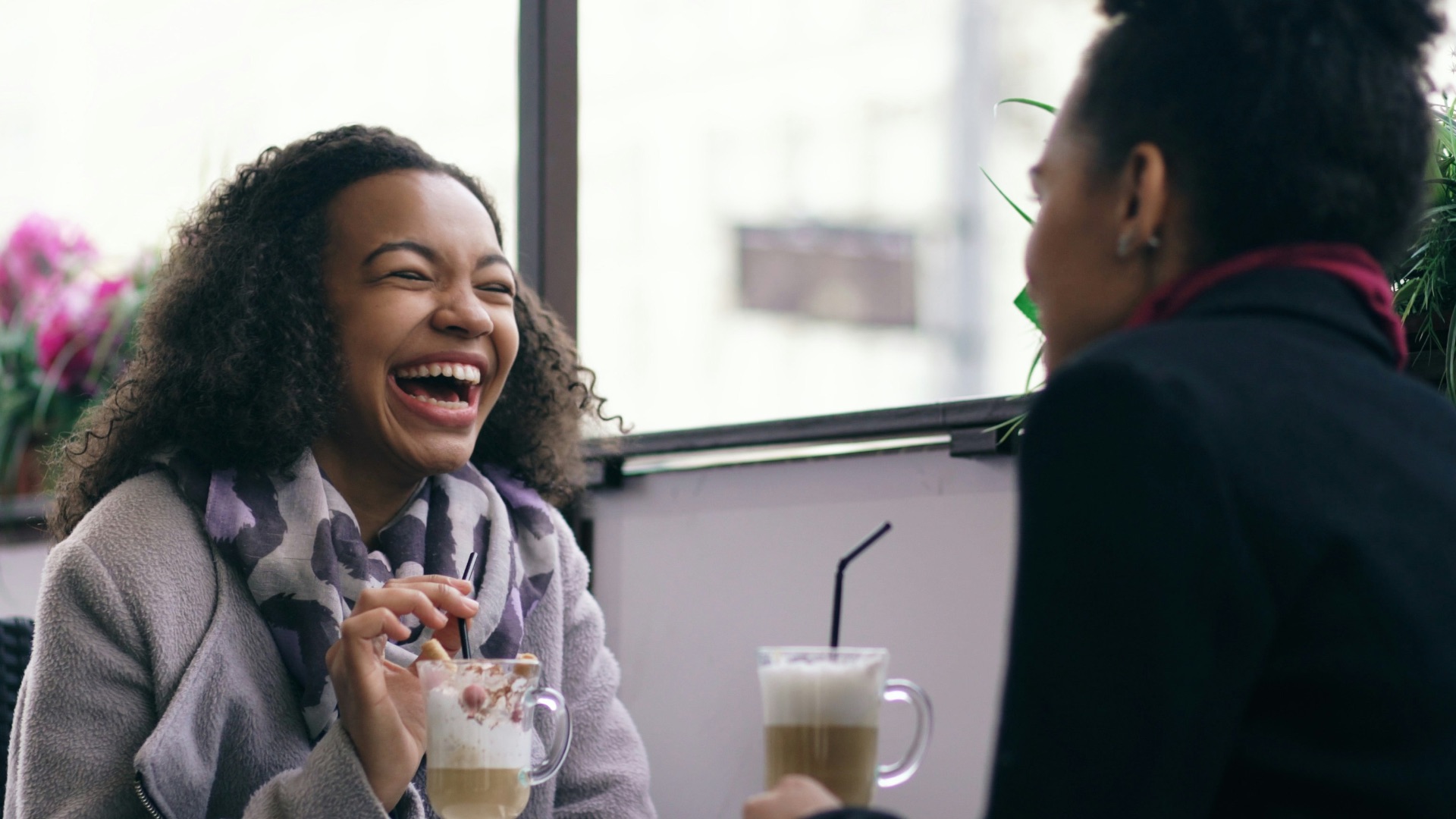 Two women laughing at a cafe table