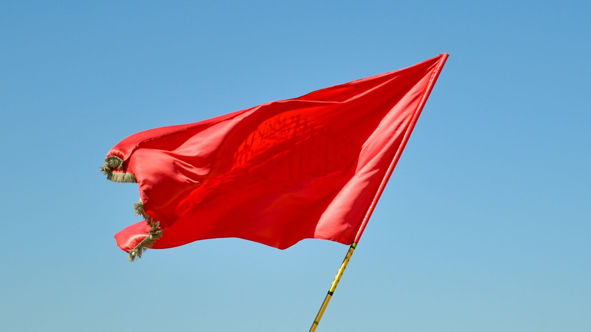 red flag on pole under blue sky during daytime