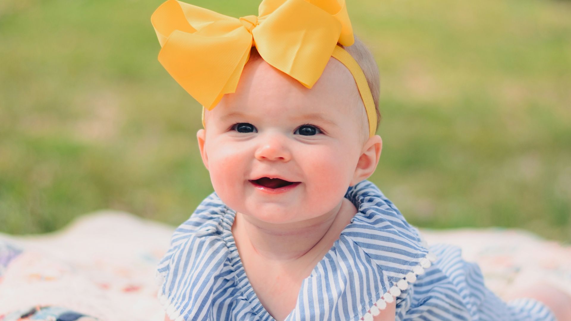 smiling baby lying forward on pink textile