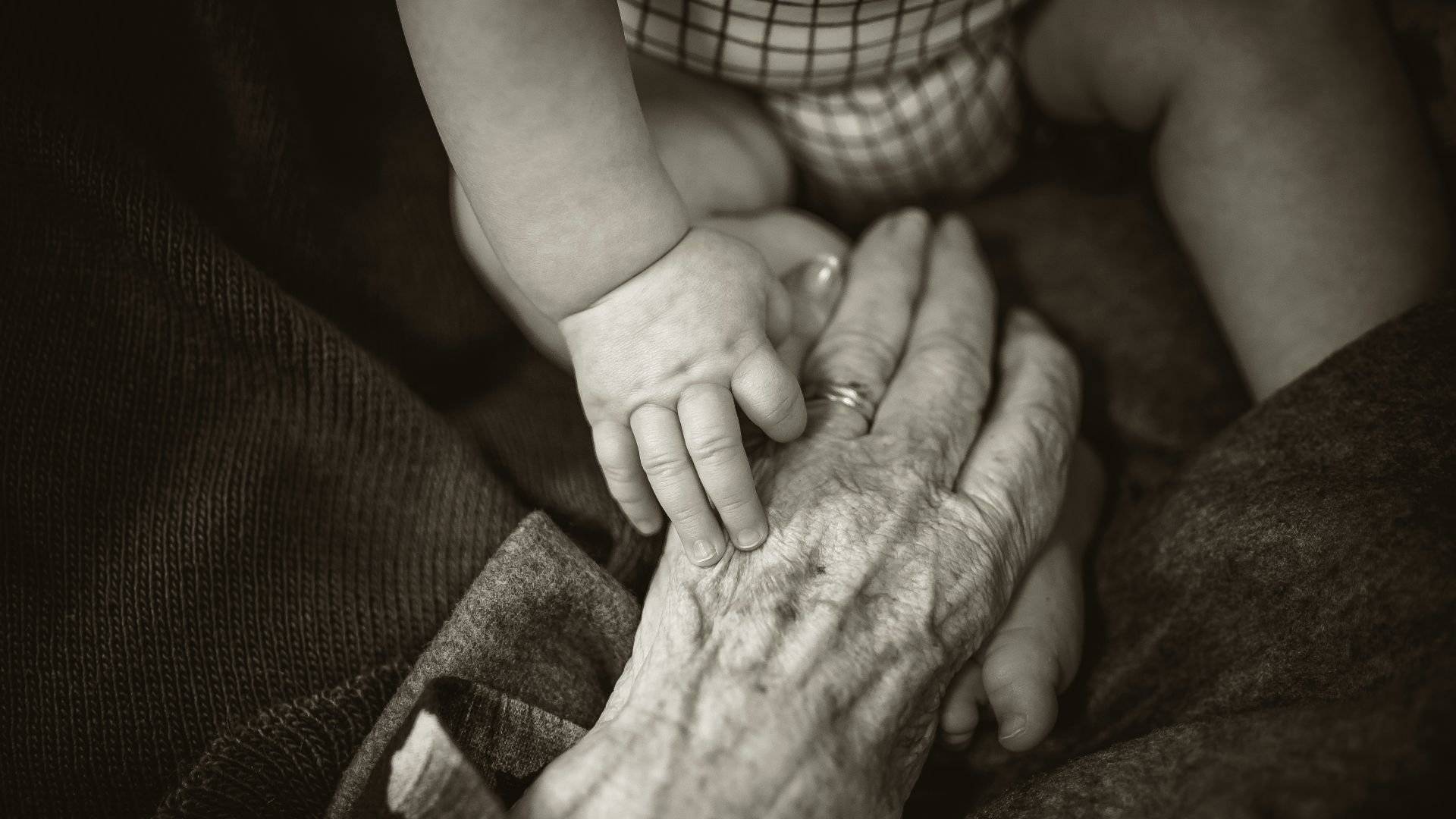 an older woman holding a baby's hand
