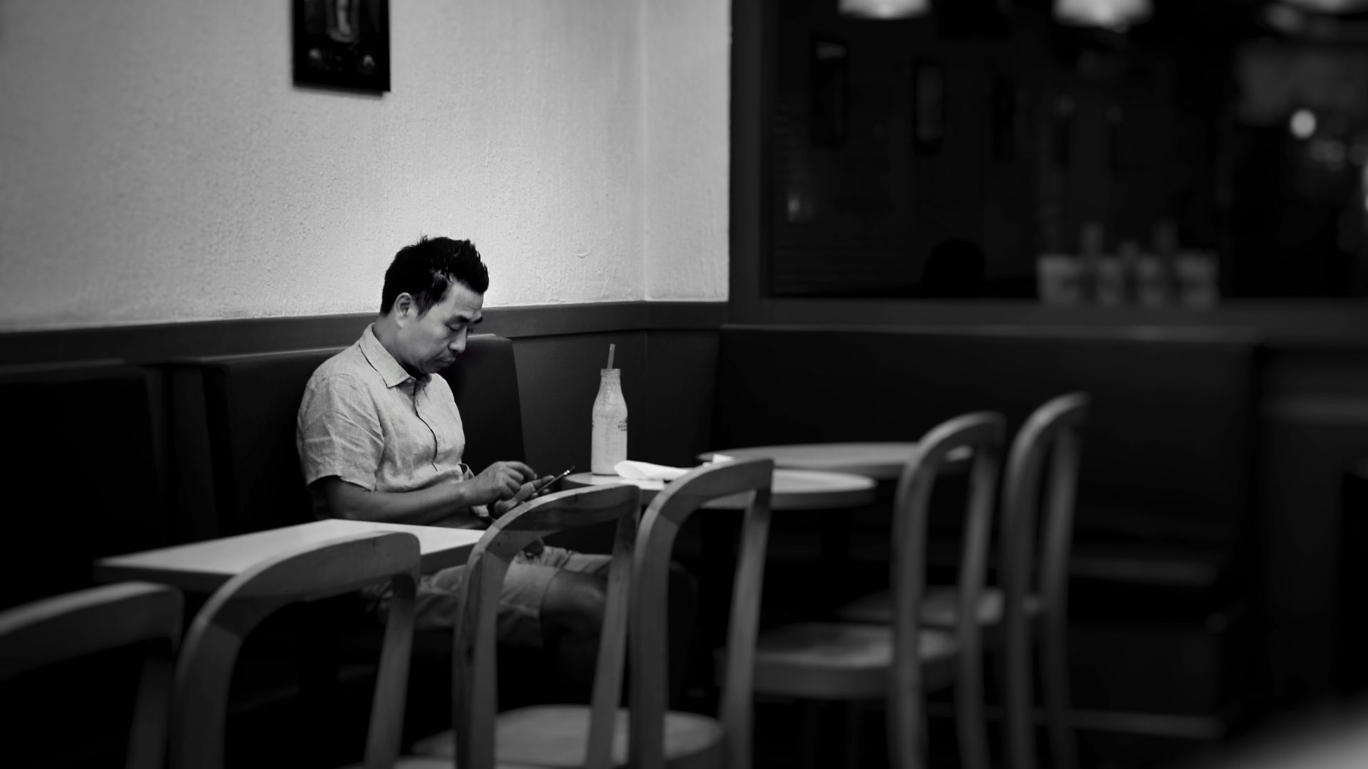 man sitting on cafe while holding smartphone