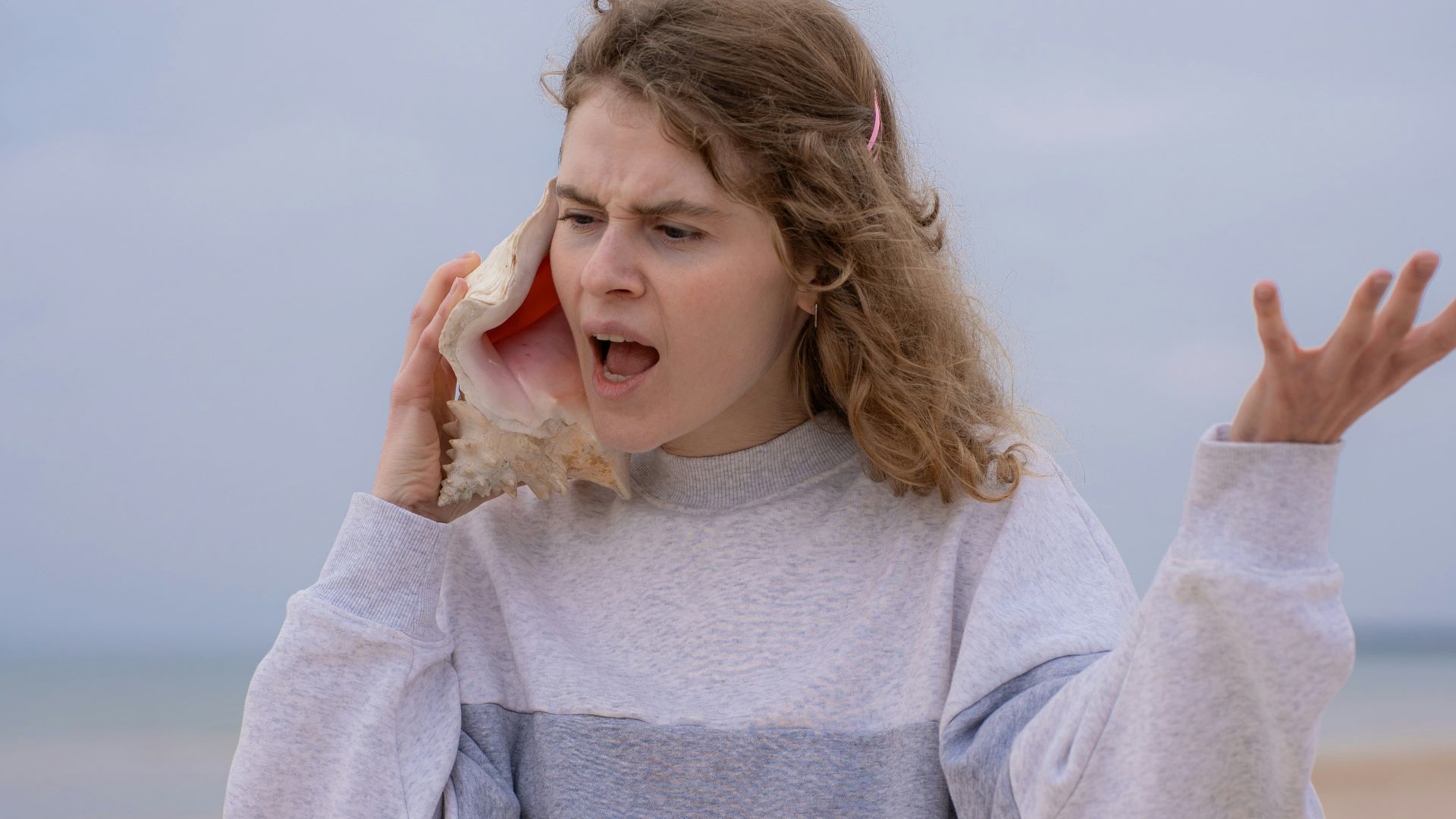 a woman on the beach holding a cell phone to her ear