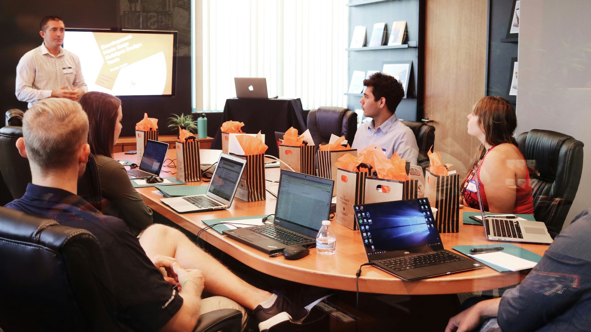 man standing in front of people sitting beside table with laptop computers