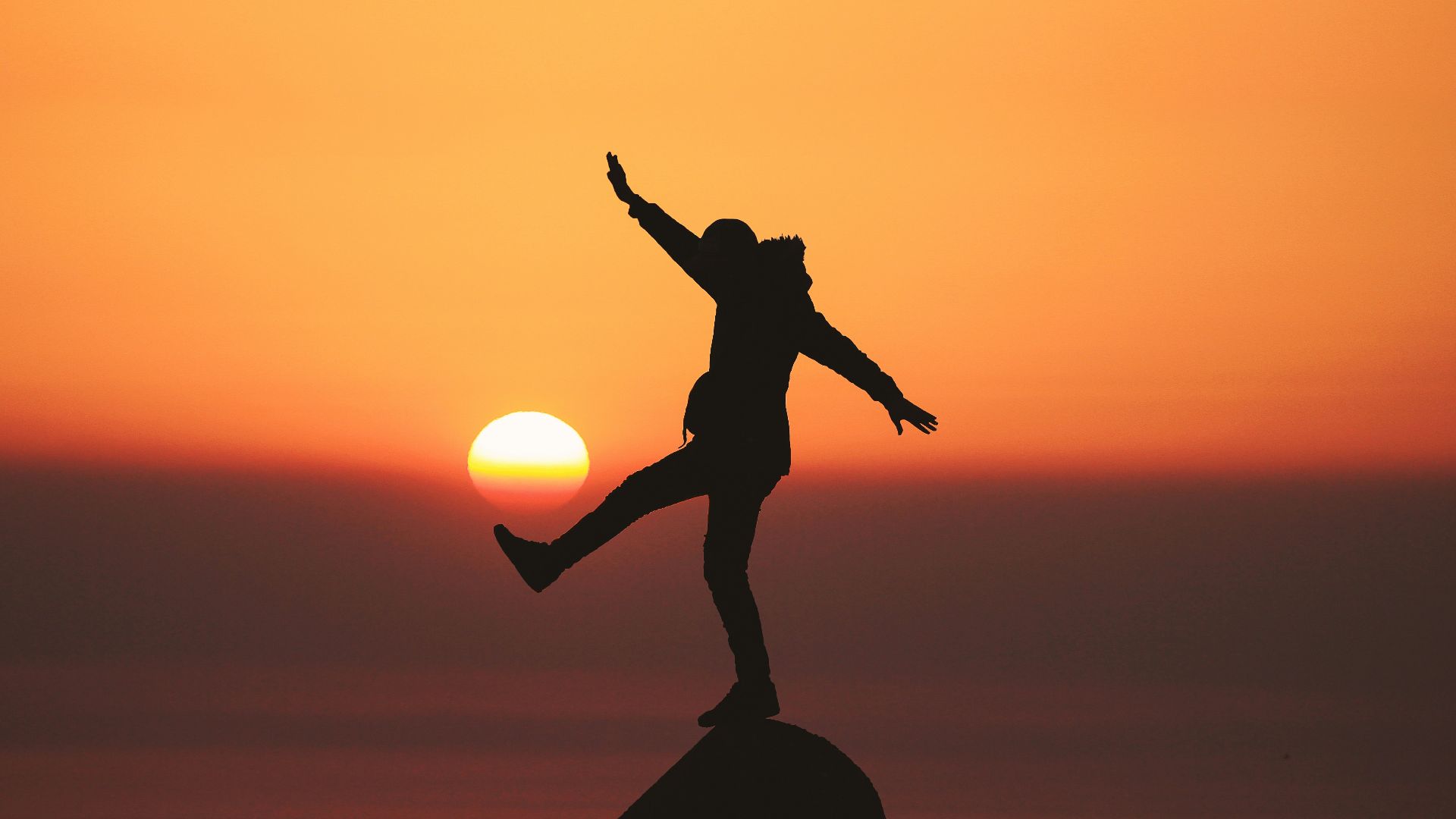 photo of silhouette photo of man standing on rock