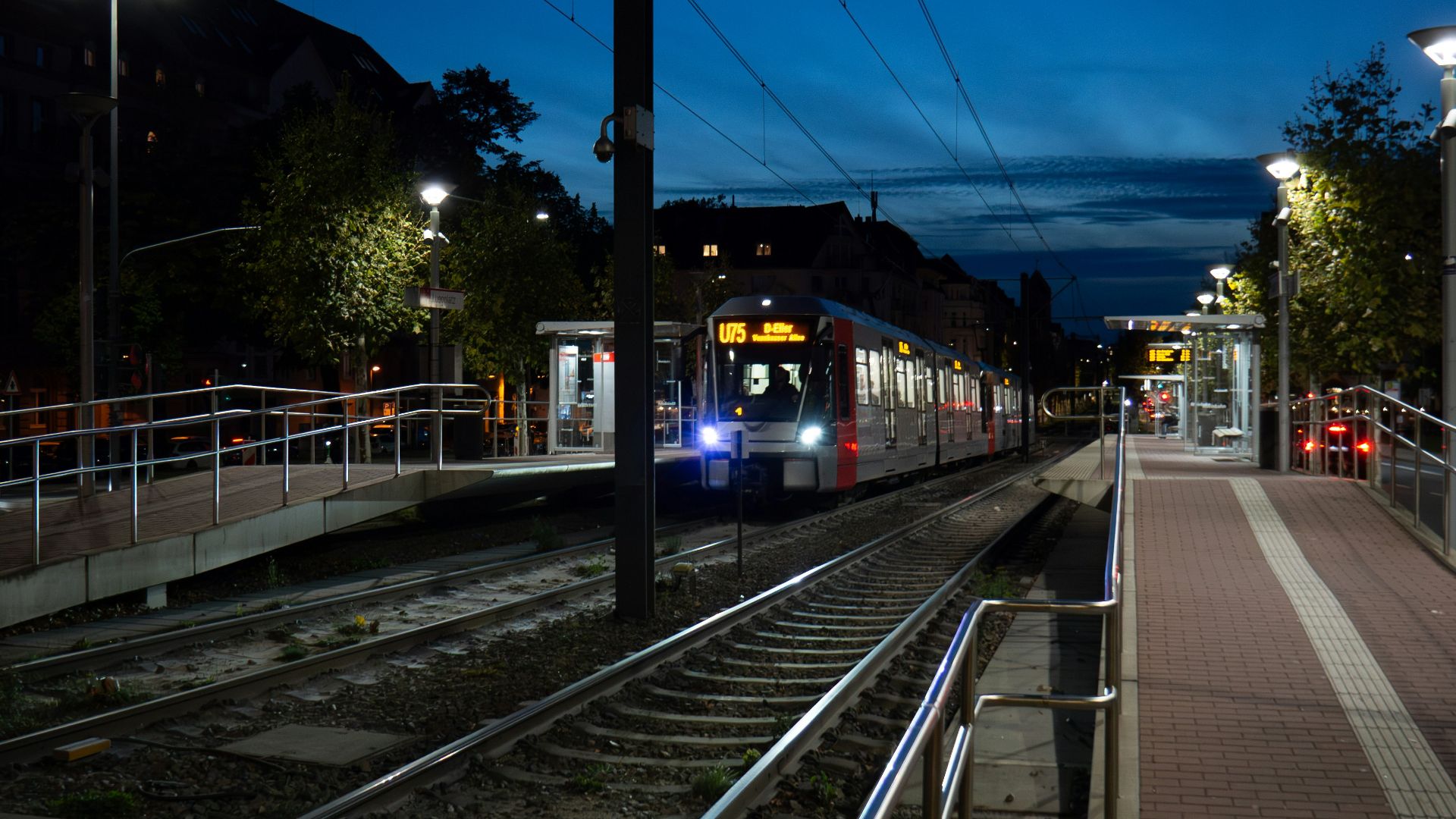 A tram arriving at a station at dusk.
