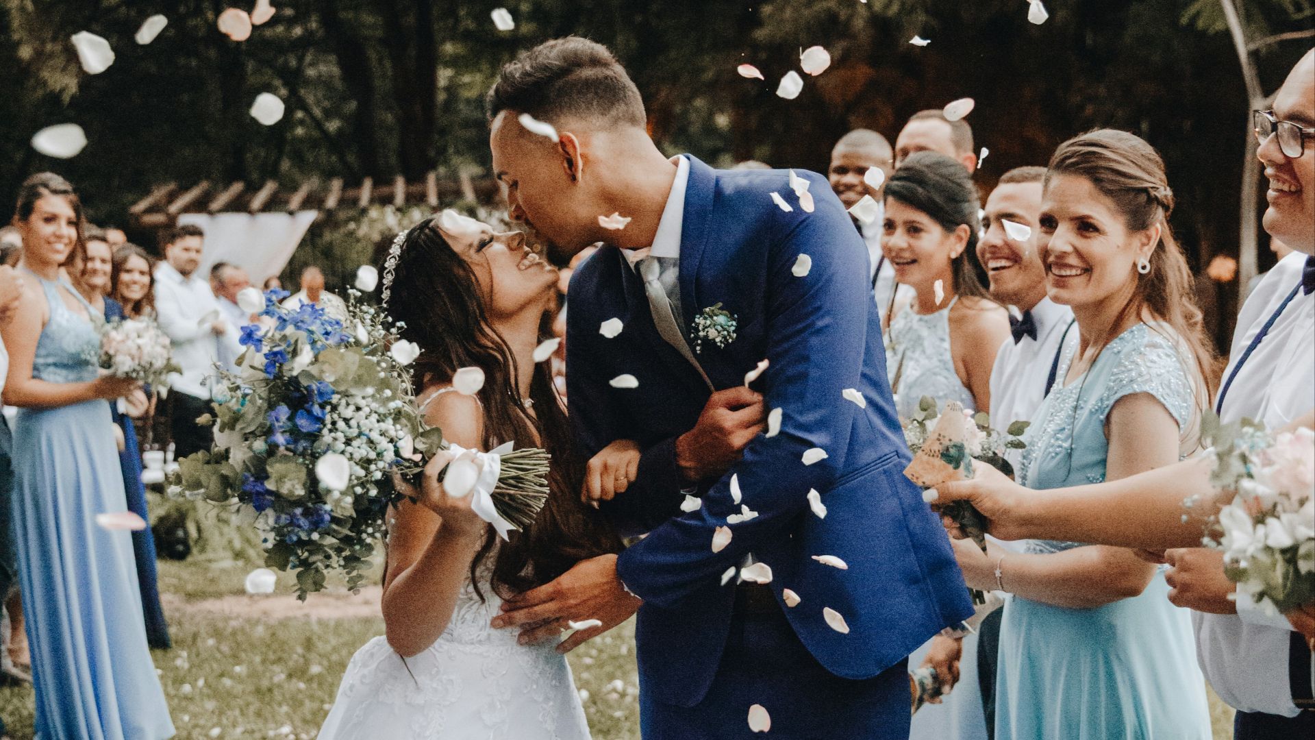 man in blue suit kissing woman in white wedding dress
