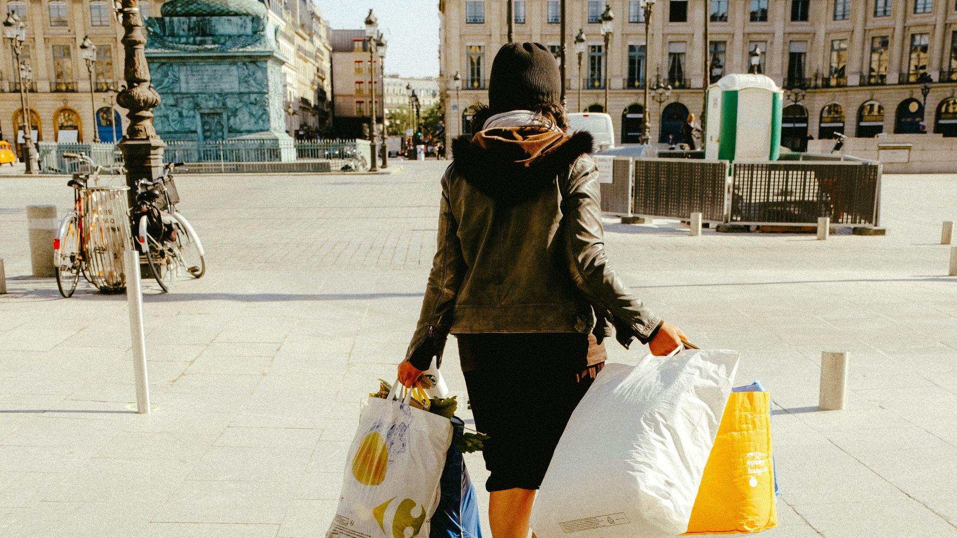 woman in black jacket and white skirt walking on sidewalk during daytime