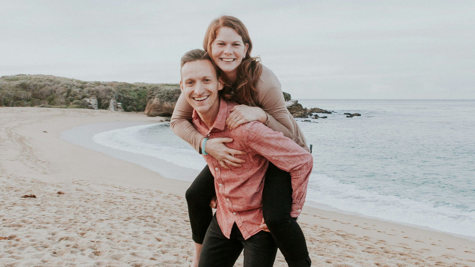man carrying woman beside seashore
