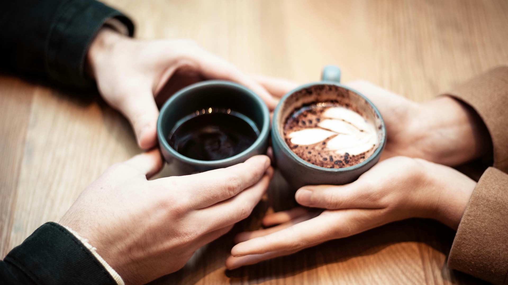 two person holding ceramic mugs with coffee