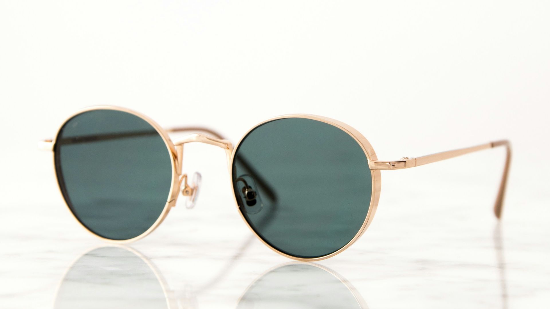 gold-colored framed hippie sunglasses on white surface