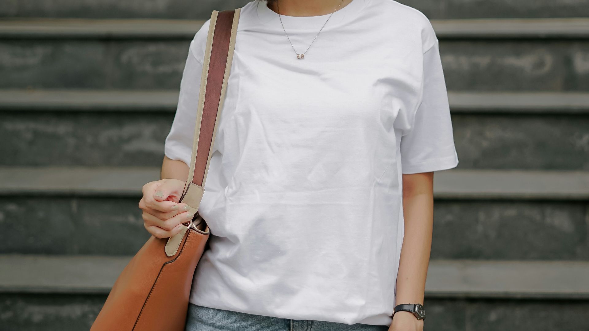 woman in white crew neck t-shirt and brown leather sling bag