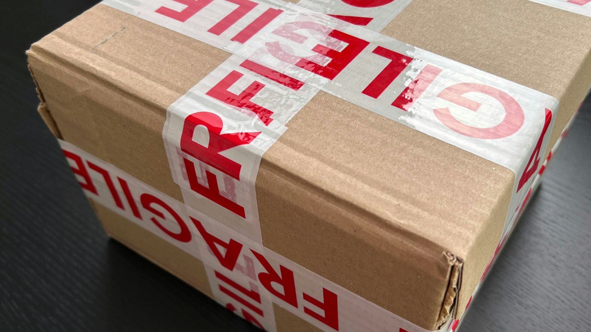 Cardboard box sealed with red fragile tape