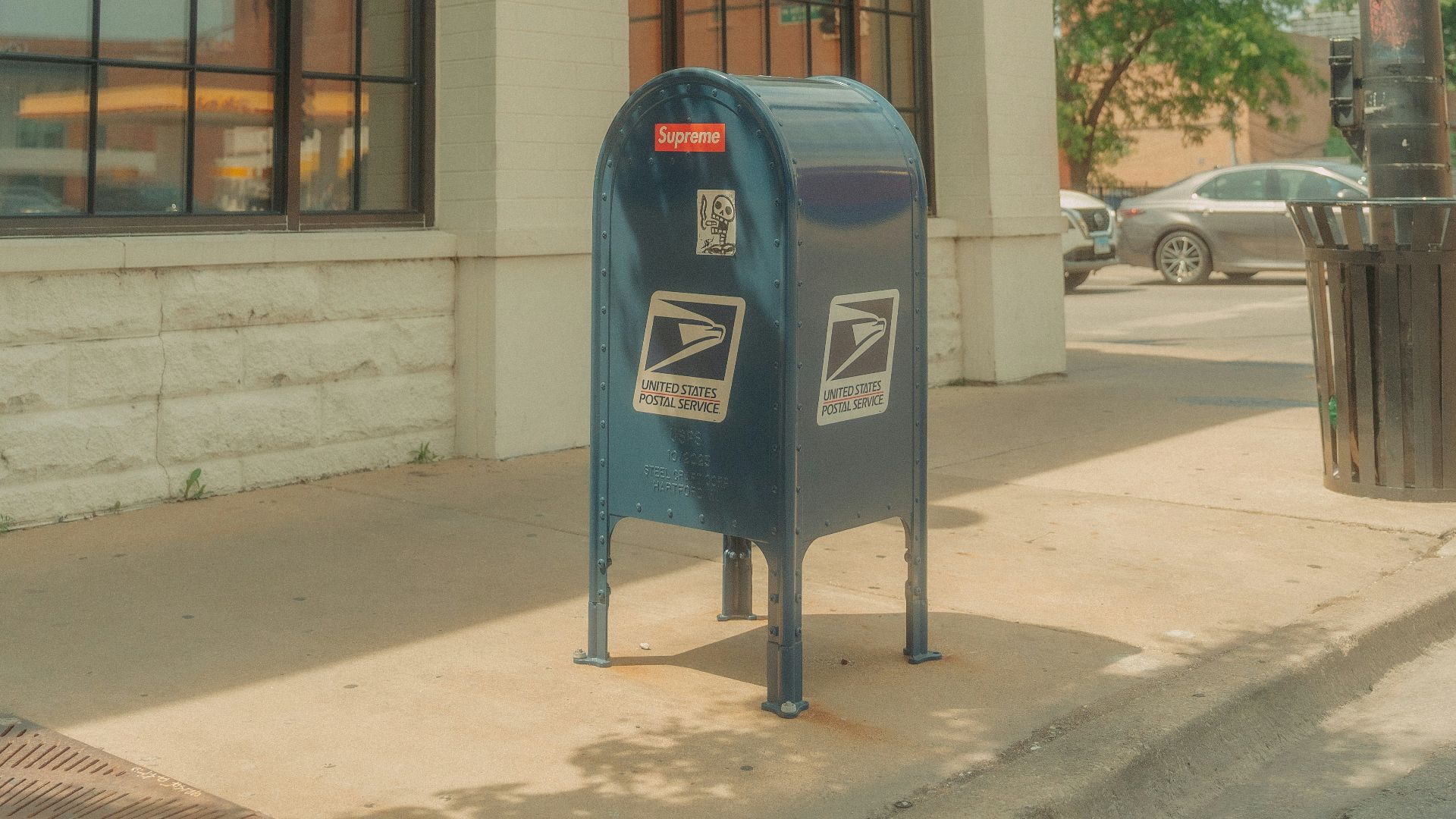 A blue mailbox sitting on the side of a street