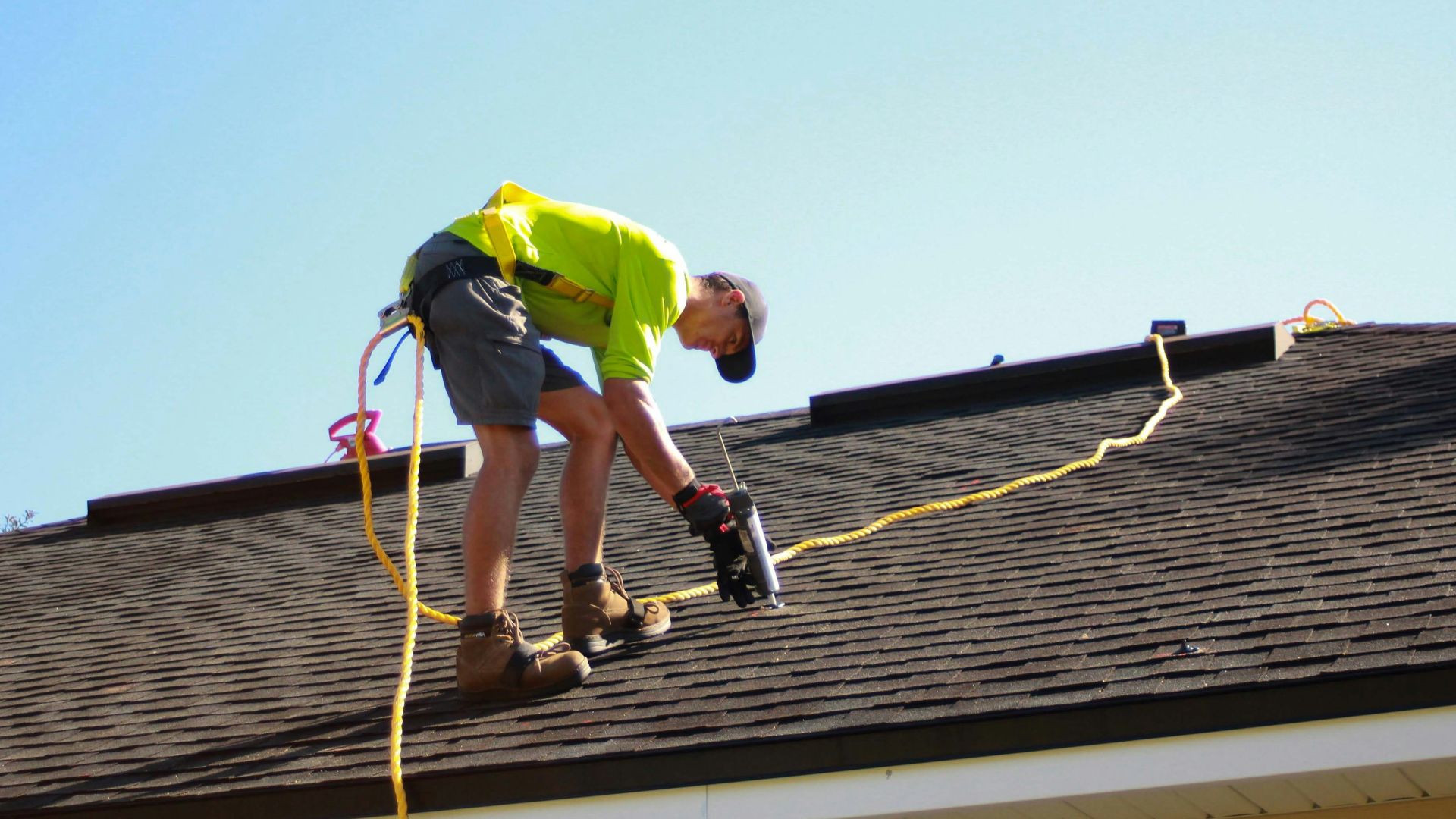 a man working on a roof with a power drill
